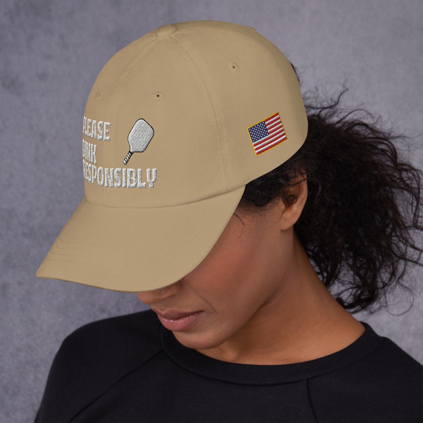 Profile of model in khaki dad hat with "PLEASE DINK RESPONSIBLY" embroidery and pickleball graphic