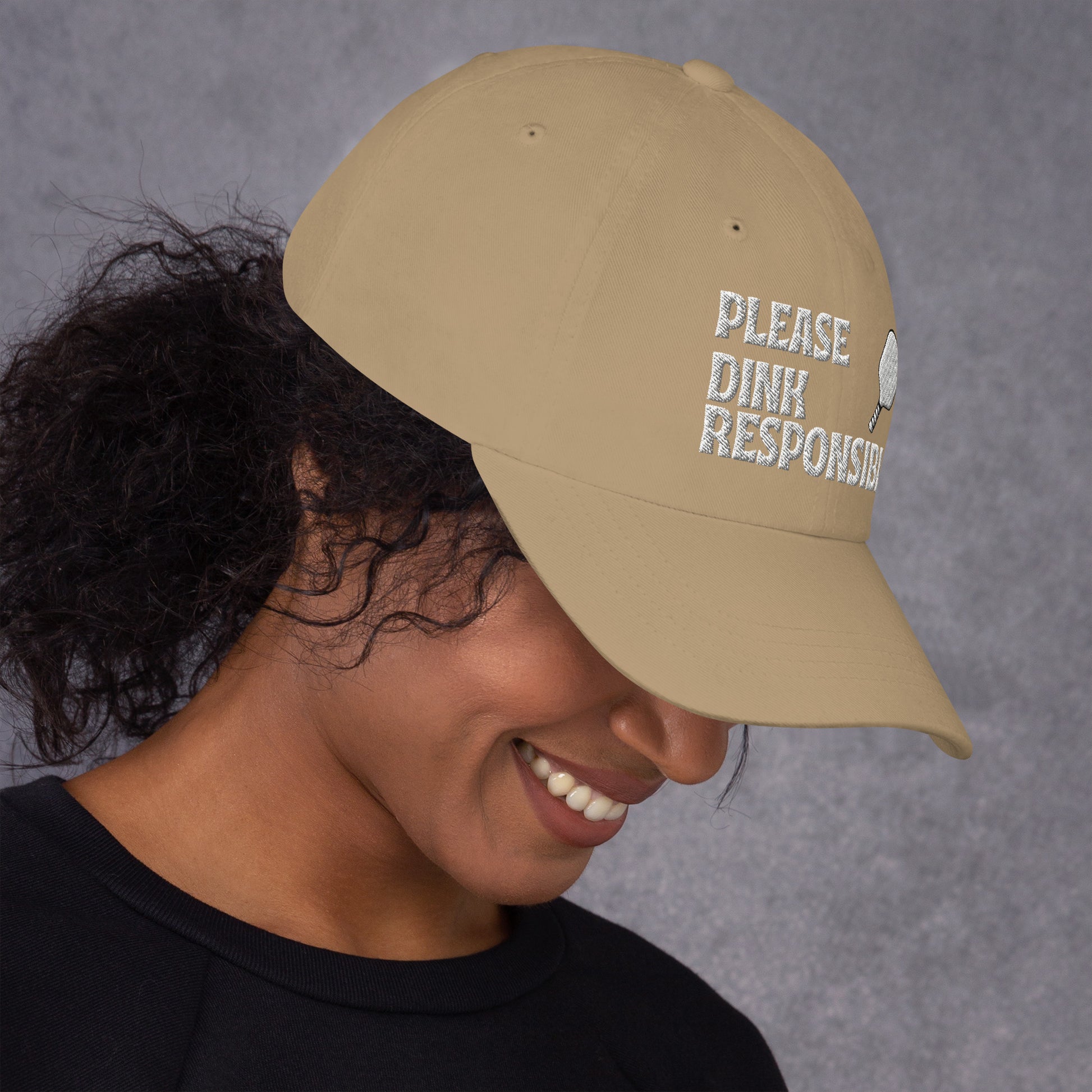 Khaki dad hat side on smiling model showing US flag patch and partial "PLEASE DINK" embroidery