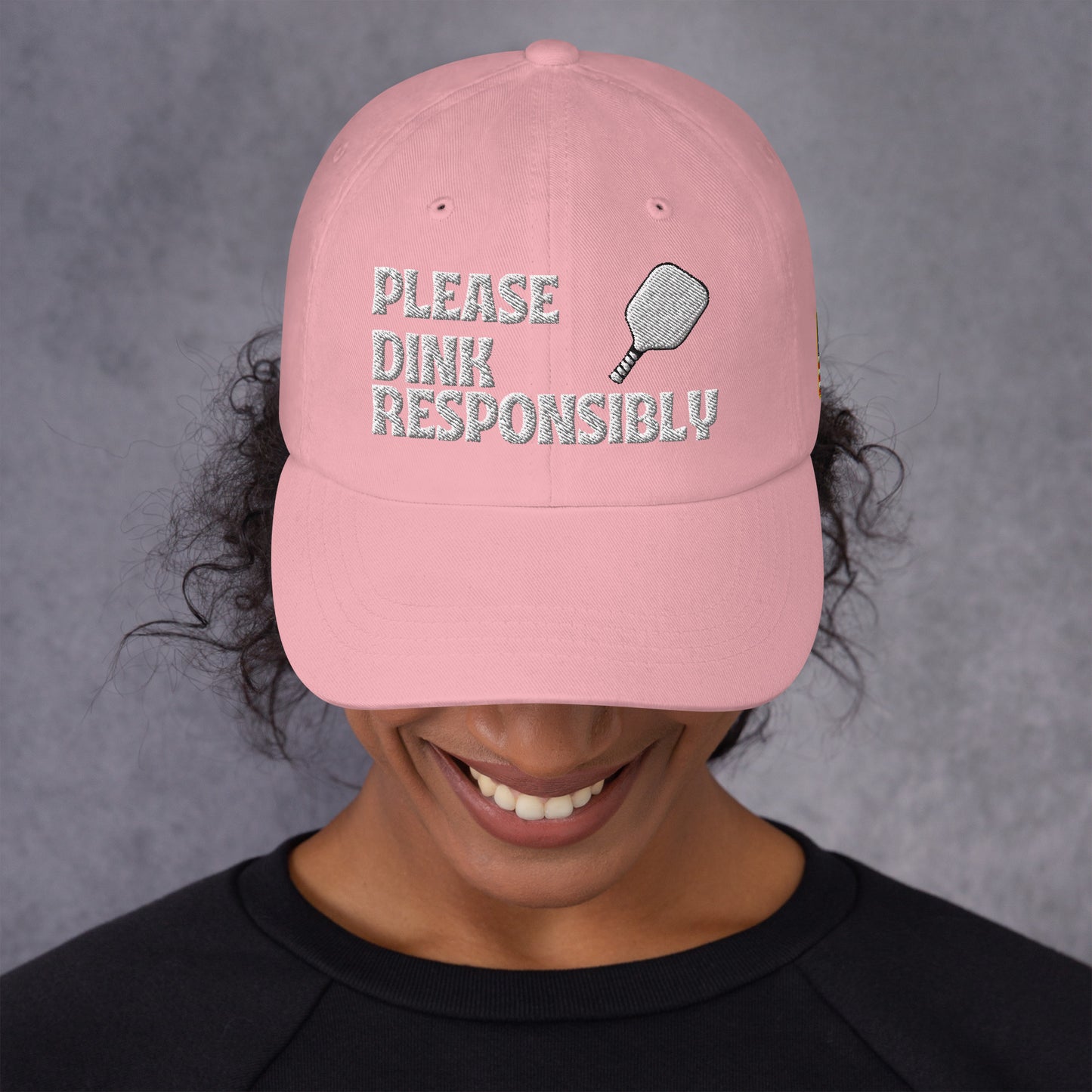 Side view of pink dad hat on model showing "PLEASE DINK RESPONSIBLY" and pickleball embroidery