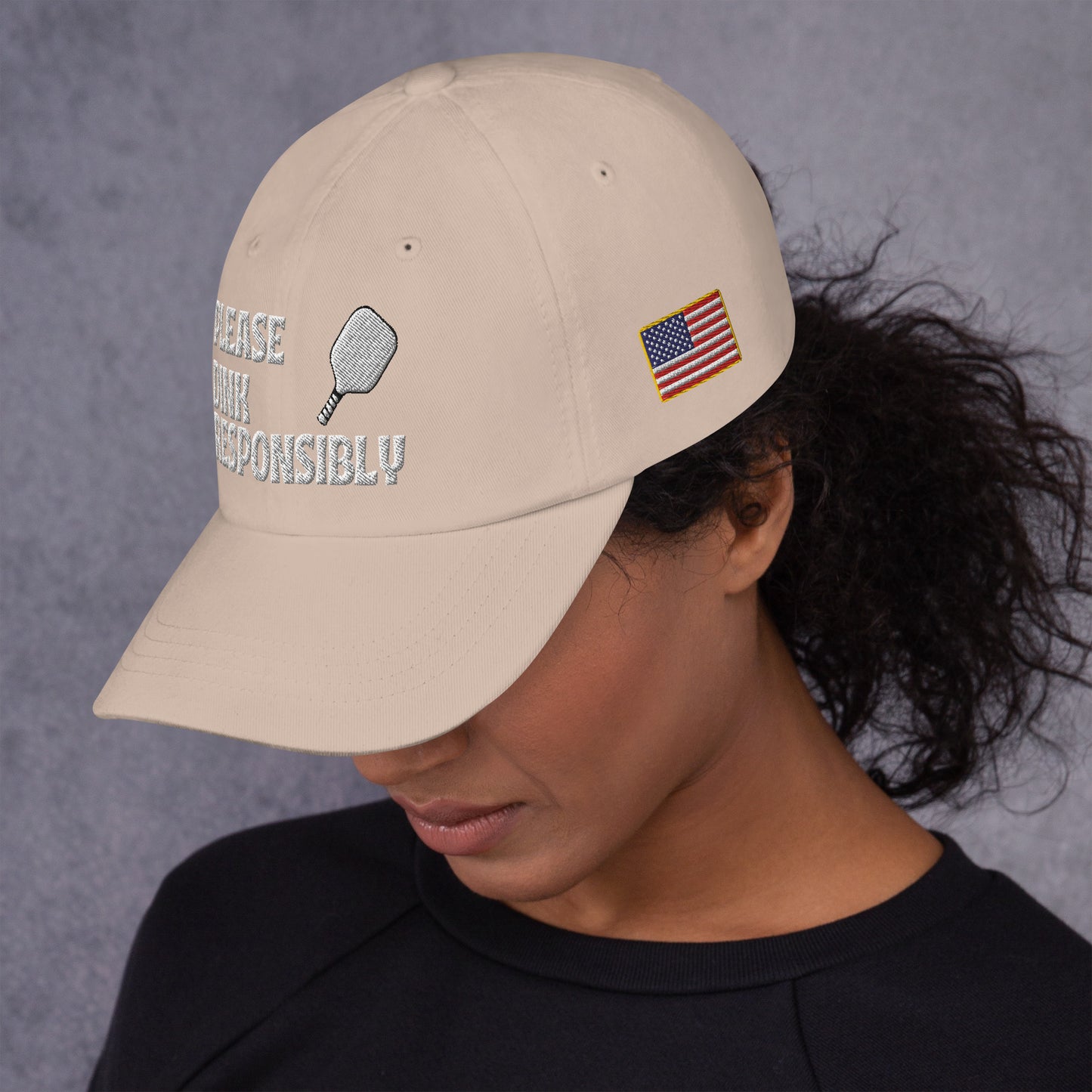 Smiling side profile in khaki dad hat displaying "PLEASE DINK RESPONSIBLY" text and paddle icon