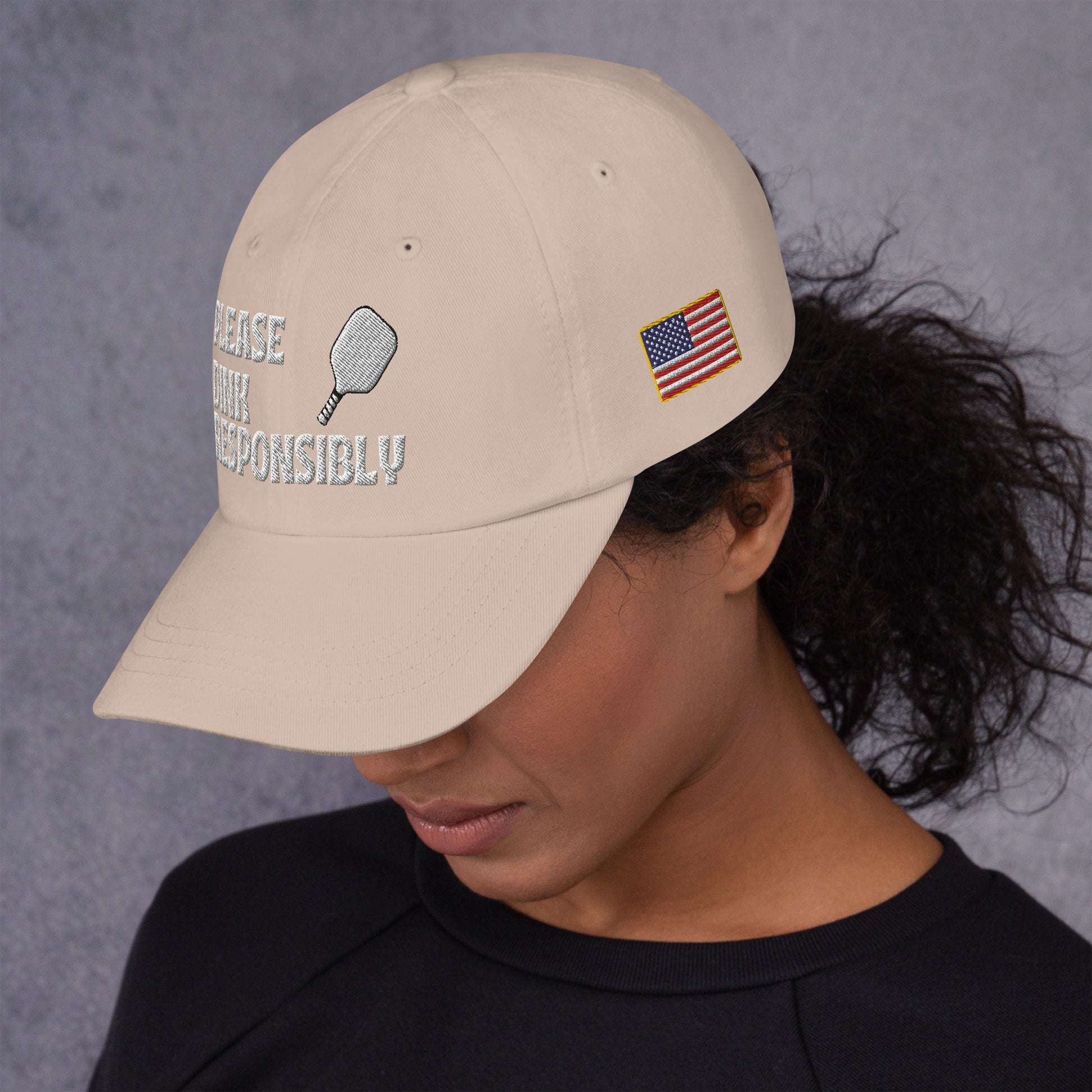 Smiling side profile in khaki dad hat displaying "PLEASE DINK RESPONSIBLY" text and paddle icon