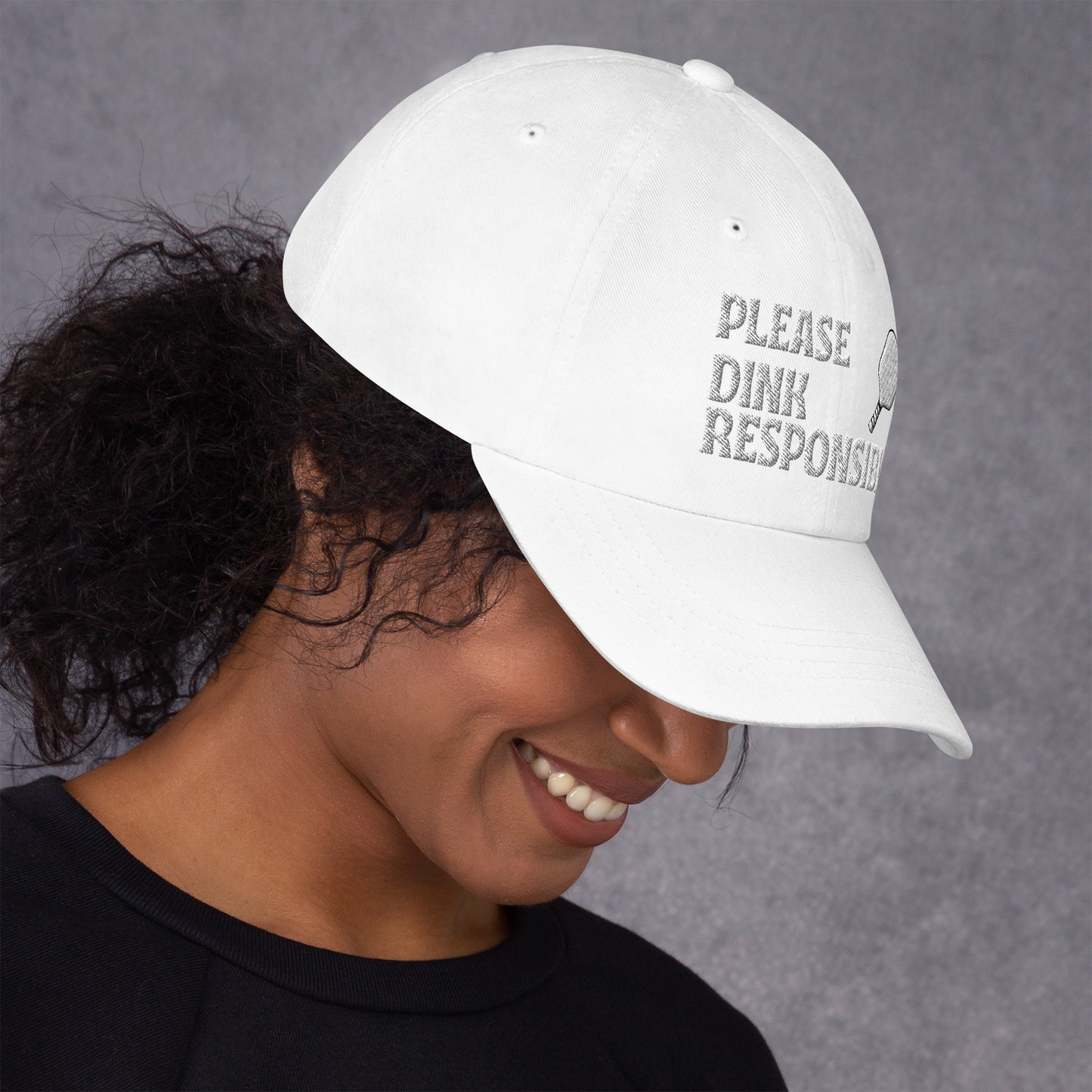 Side profile of white dad hat on model, arched "PLEASE DINK RESPONSIBLY" embroidery, paddle and US flag