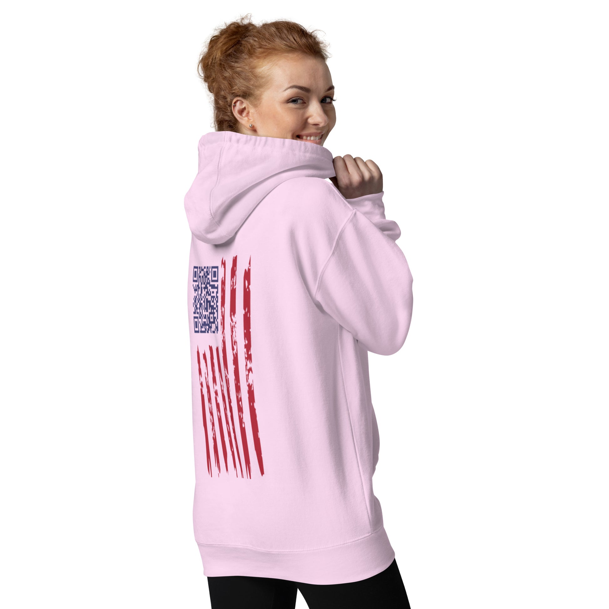 Redhead model turning to smile in light pink hoodie, revealing embroidered back flag with hidden QR code