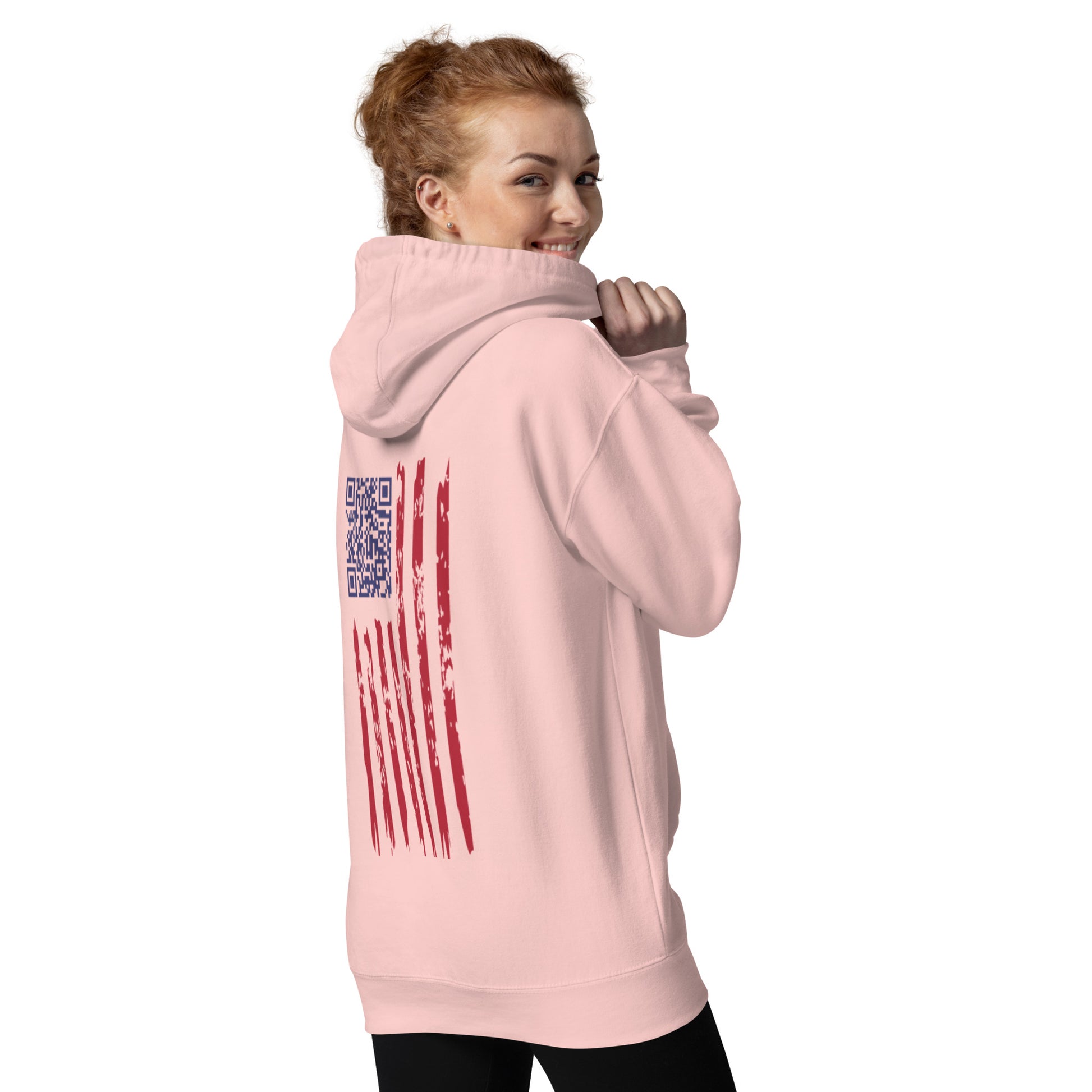 Redhead model smiling sideways in light pink hoodie, back view flaunting distressed flag & QR embroidery