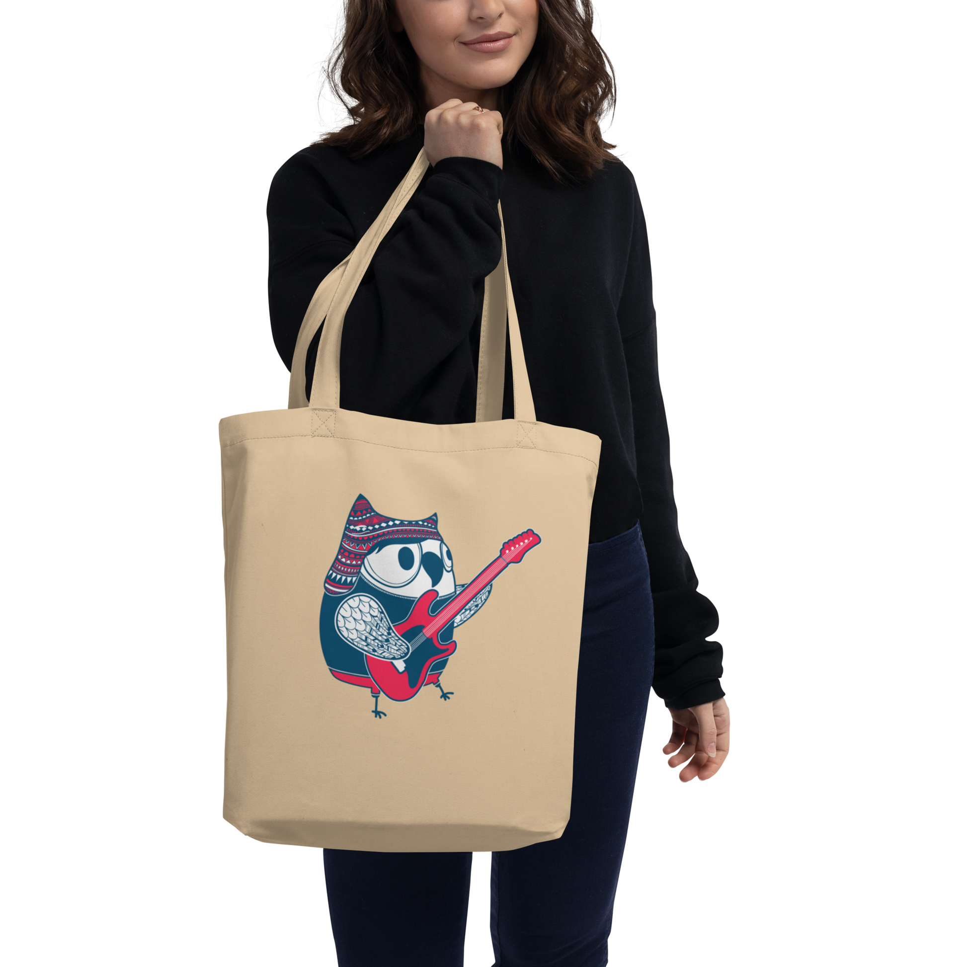 Model slinging oyster eco tote bag featuring wide-eyed owl jamming guitar in pom hat — sustainable shred vibes
