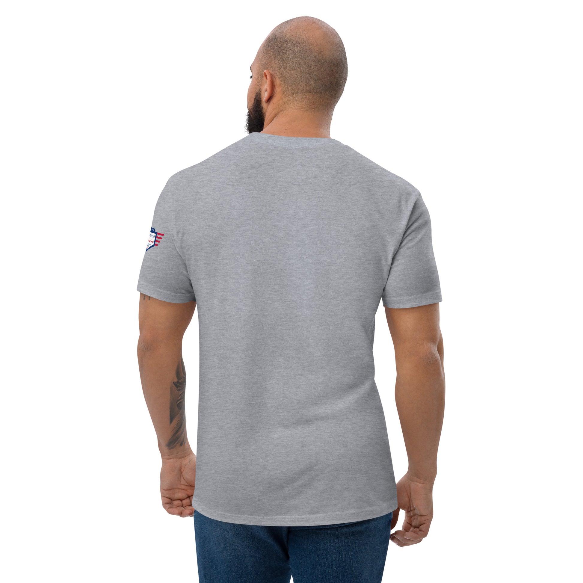 Back view of bearded model in plain heather gray fitted shirt, American flag sleeve patch