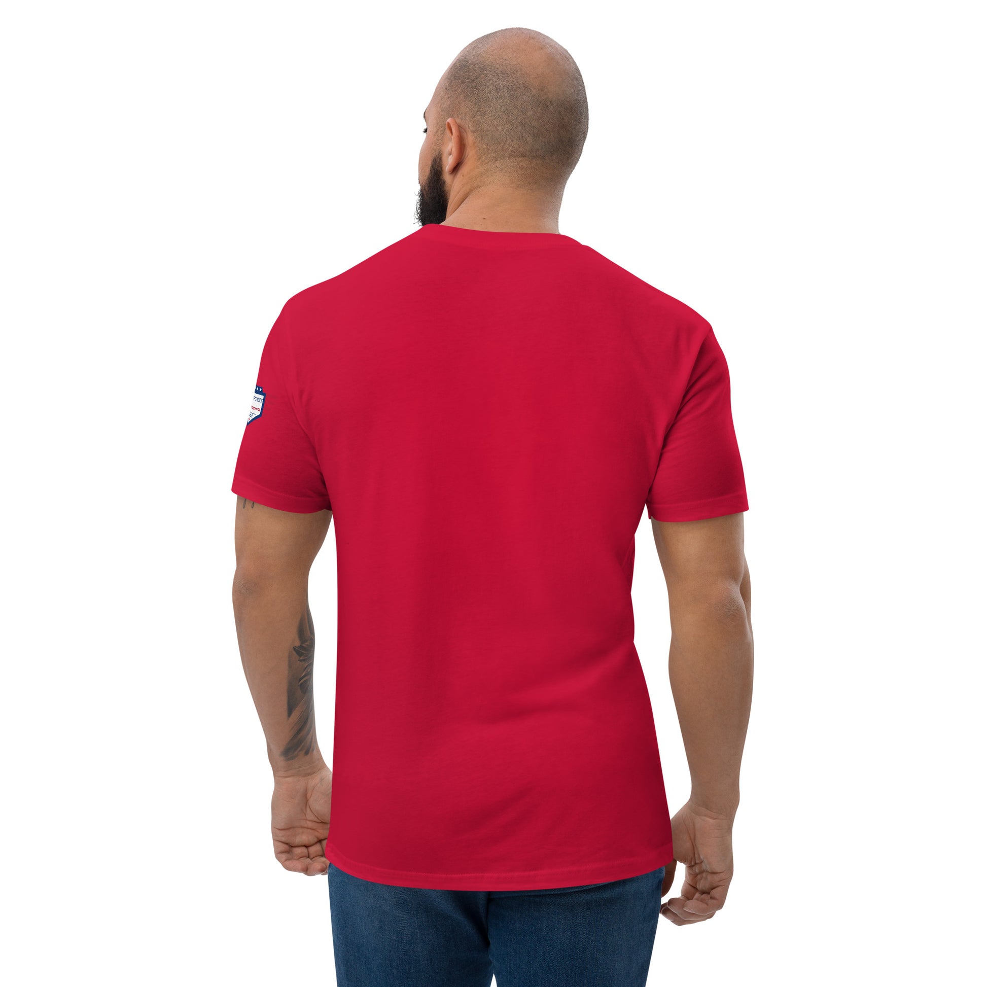 Back of red fitted tee on bearded model, clean plain style with USA flag patch on sleeve