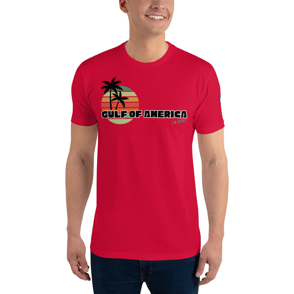 Front view of smiling model in red Gulf of America fitted tee, retro palm trees over sunset gradient and "Gulf of America" text