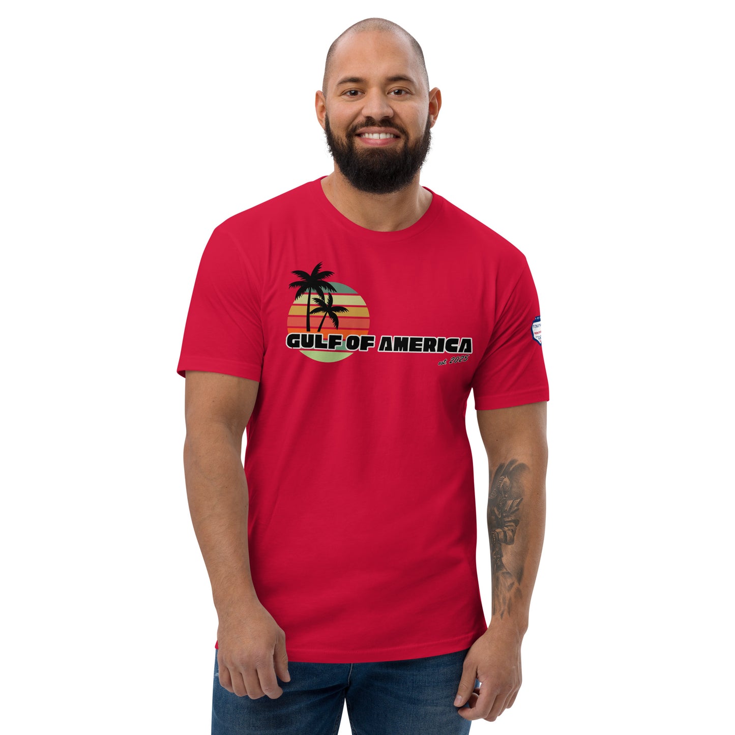 Grinning model owns red Gulf of America fitted shirt, front view flaunting palm tree sunset graphic and bold text, flag sleeve
