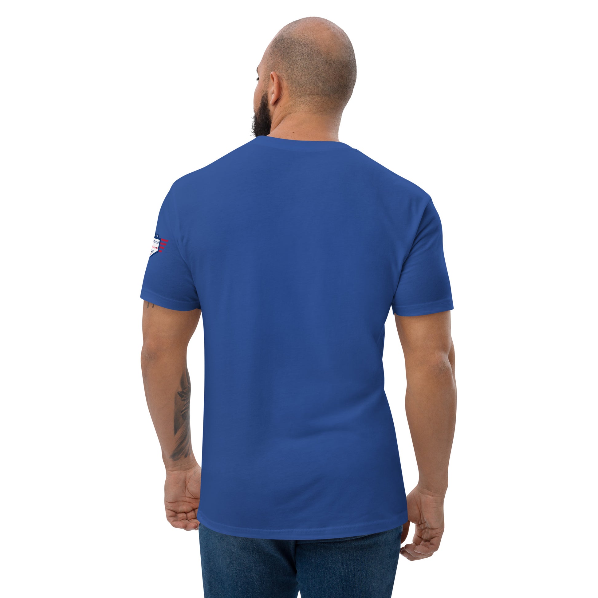 Back view of royal blue fitted shirt on bearded model in jeans, plain with small USA flag sleeve patch