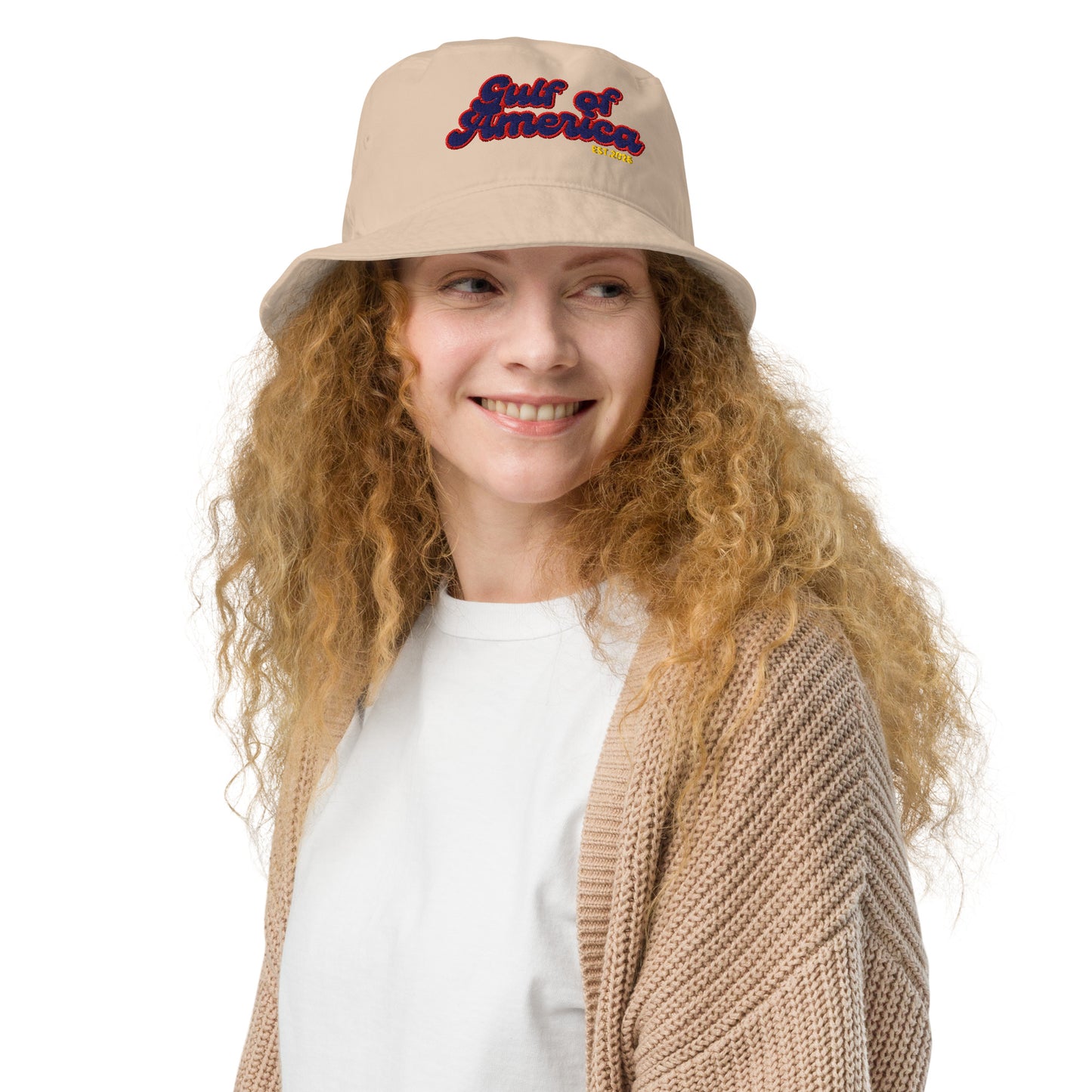 Smiling curly-haired model rocking beige bucket hat with "Gulf of America" in pink-orange and blue retro font