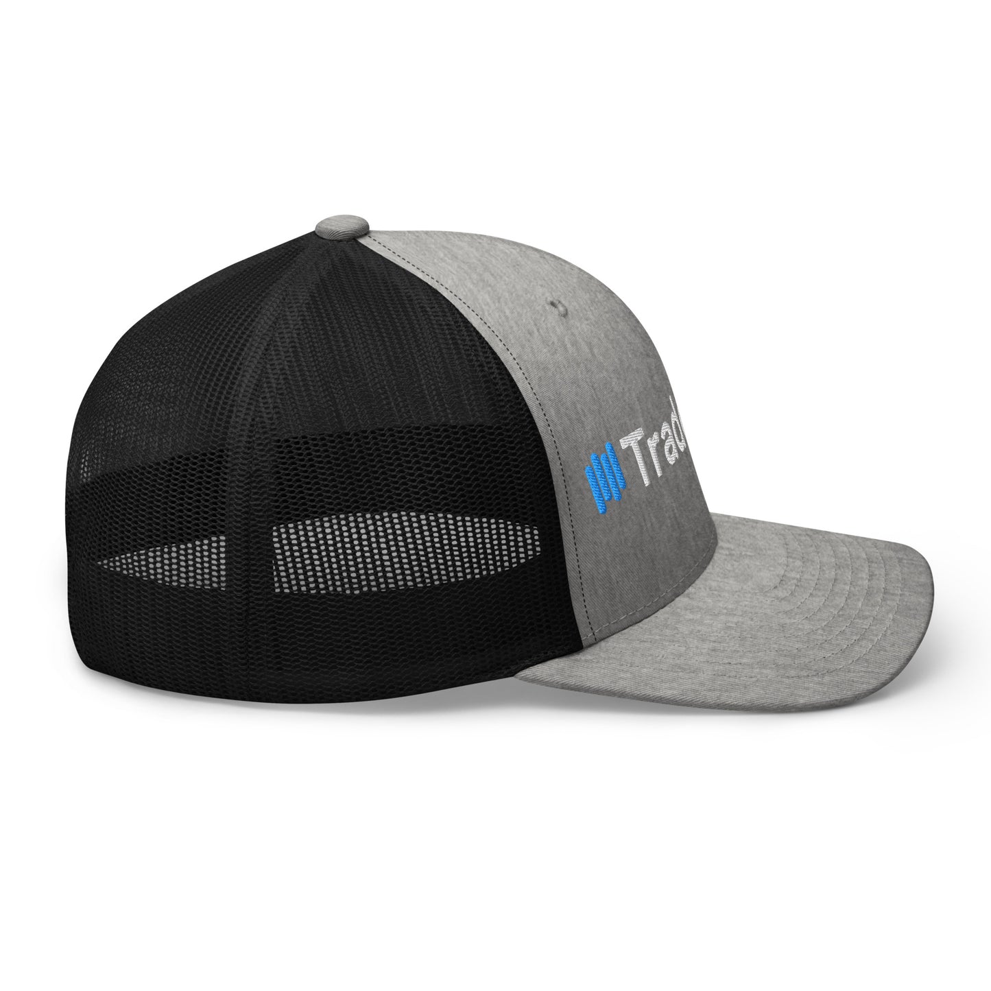 Angled front-left view of gray/black trucker cap, bold 3D puff "||TradeCaster" embroidery stealing the show