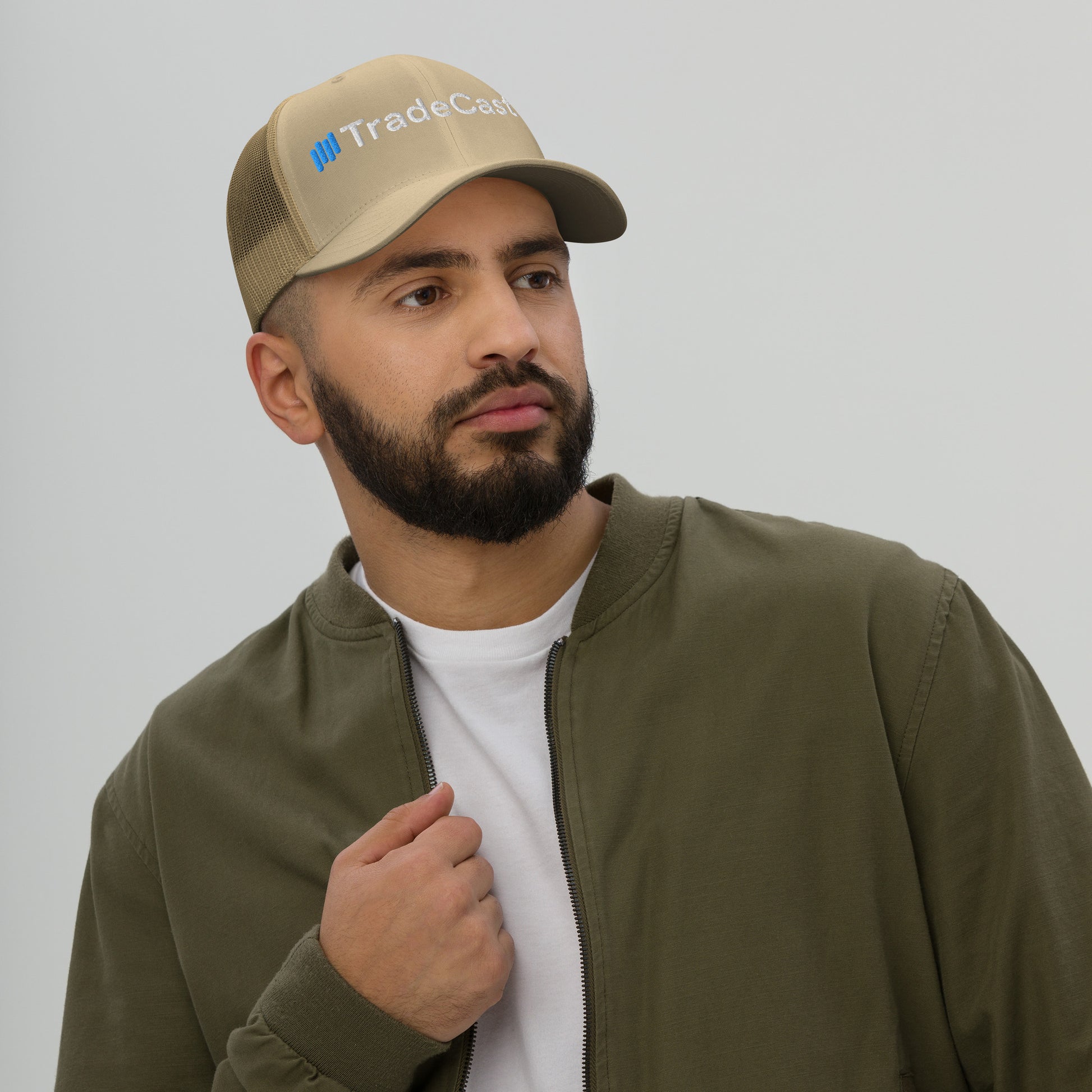 Side view of bearded guy in caramel TradeCaster mesh-back cap, green jacket, partial blue-accented embroidery