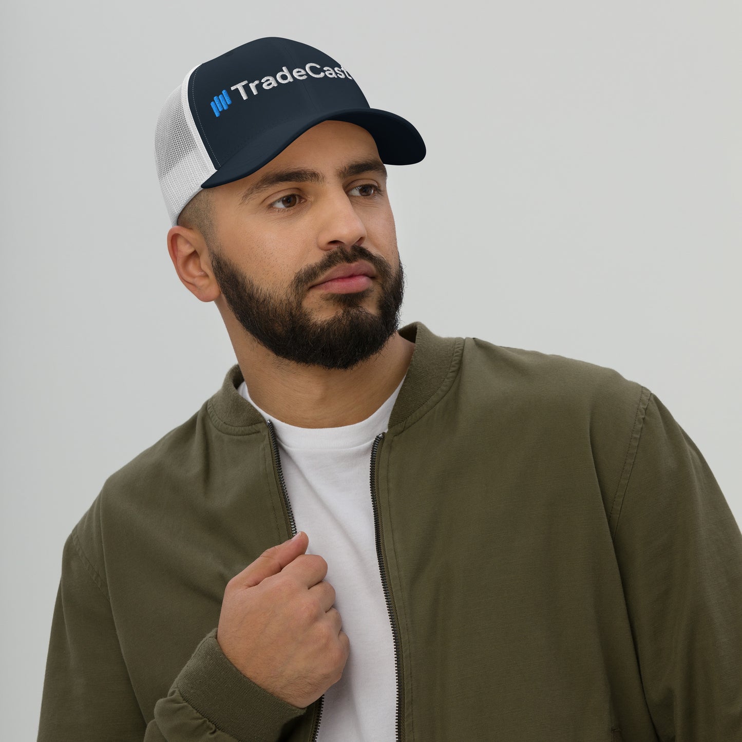 Side view bearded model in navy/white TradeCaster cap, hand to face, classic trucker profile