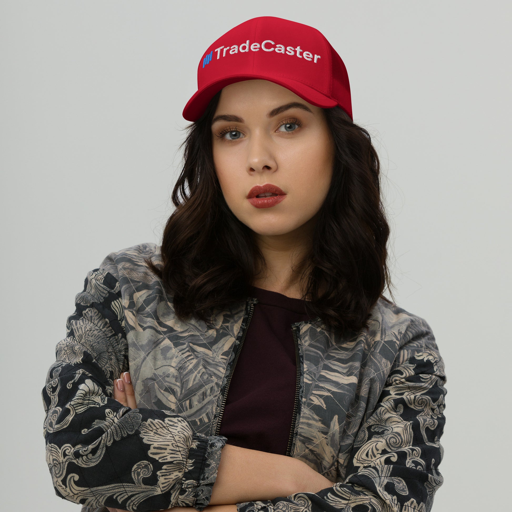 Woman channeling boss vibes in red TradeCaster cap front, arms crossed, bold white embroidery pops