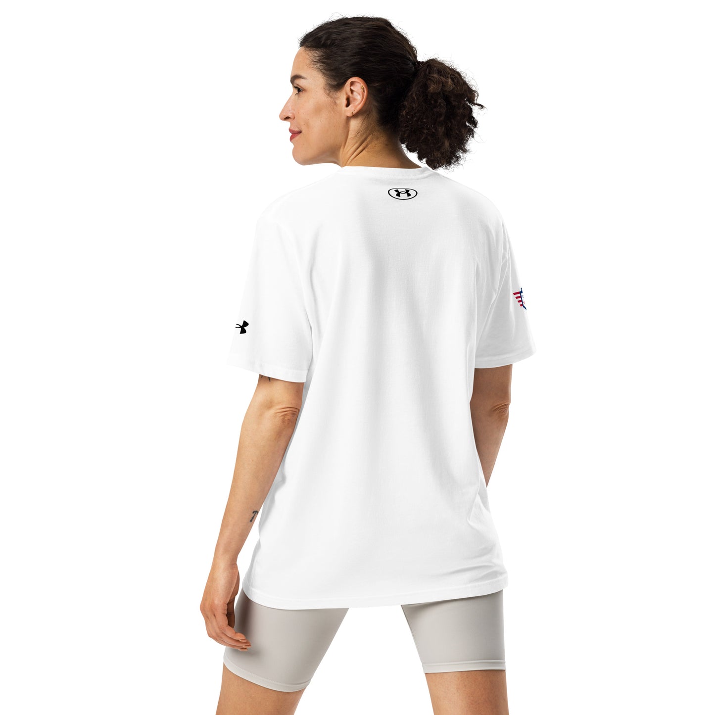 Back view of plain white Under Armour athletic tee on woman, small logo between shoulders, grey shorts