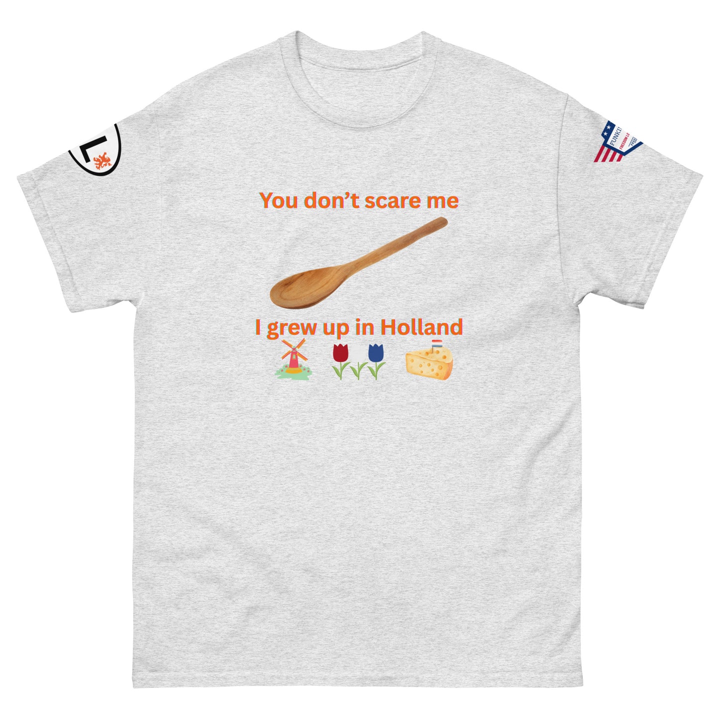 Front view of light gray unisex tee with orange "You don't scare me, I grew up in Holland" print, wooden spoon, windmill/tulip/cheese emojis, sleeve patches