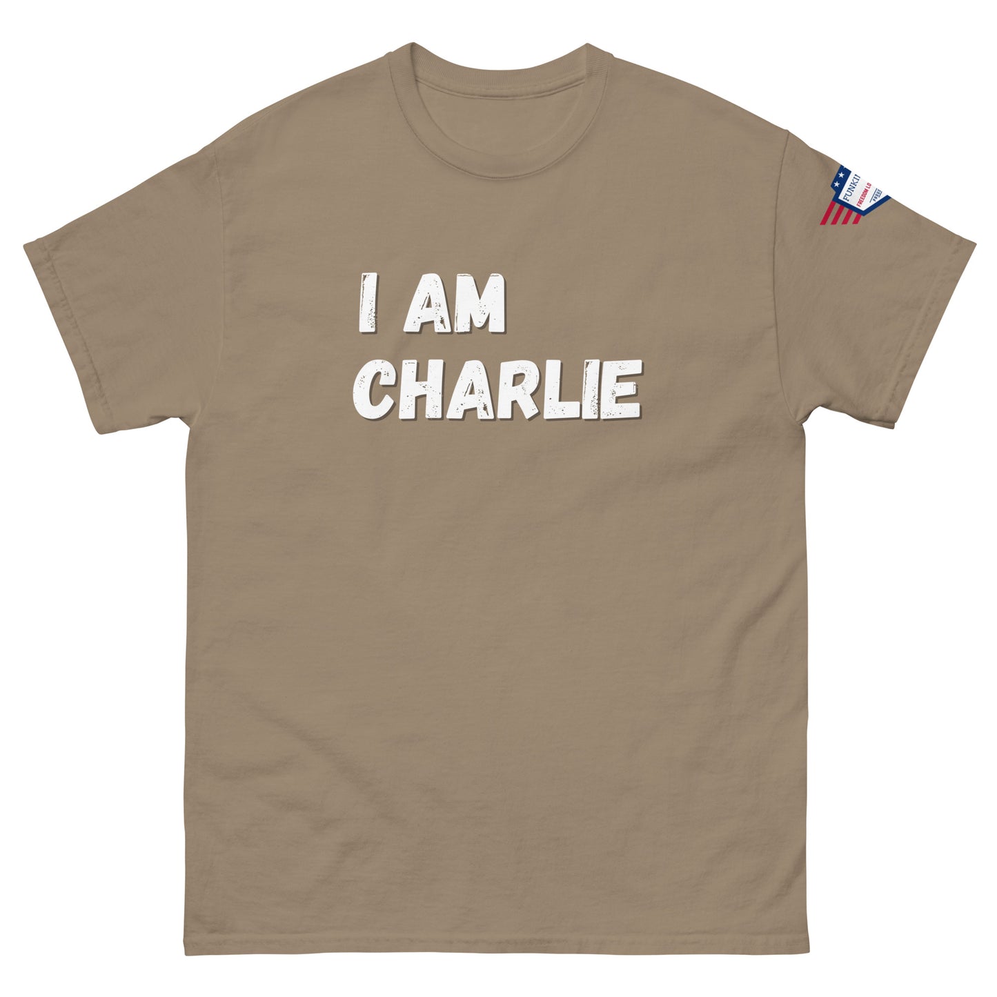 Front view of tan unisex tee with bold white "I AM CHARLIE" print and small American flag sleeve patch