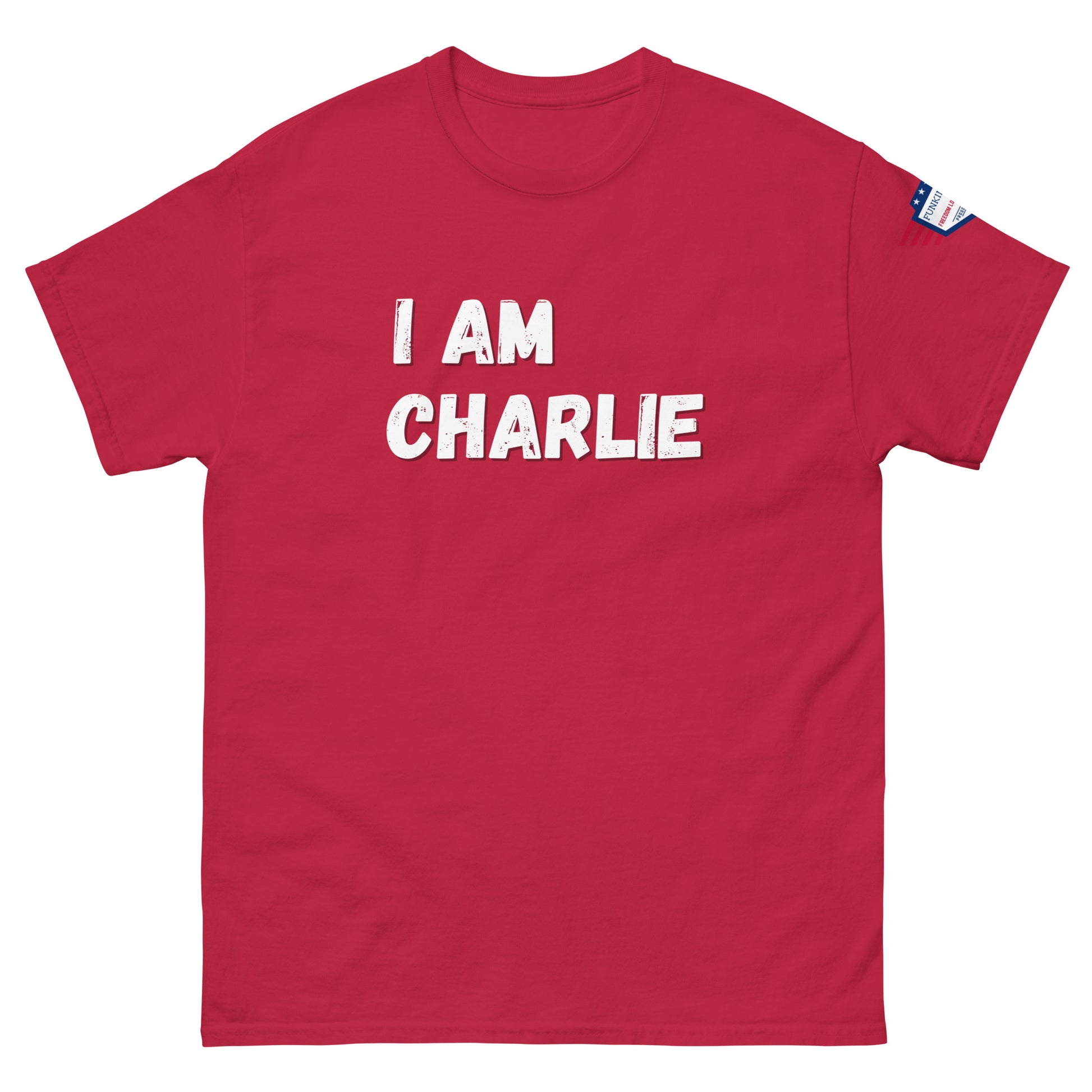 Front view of red unisex tee with bold white "I AM CHARLIE" print and small American flag sleeve patch