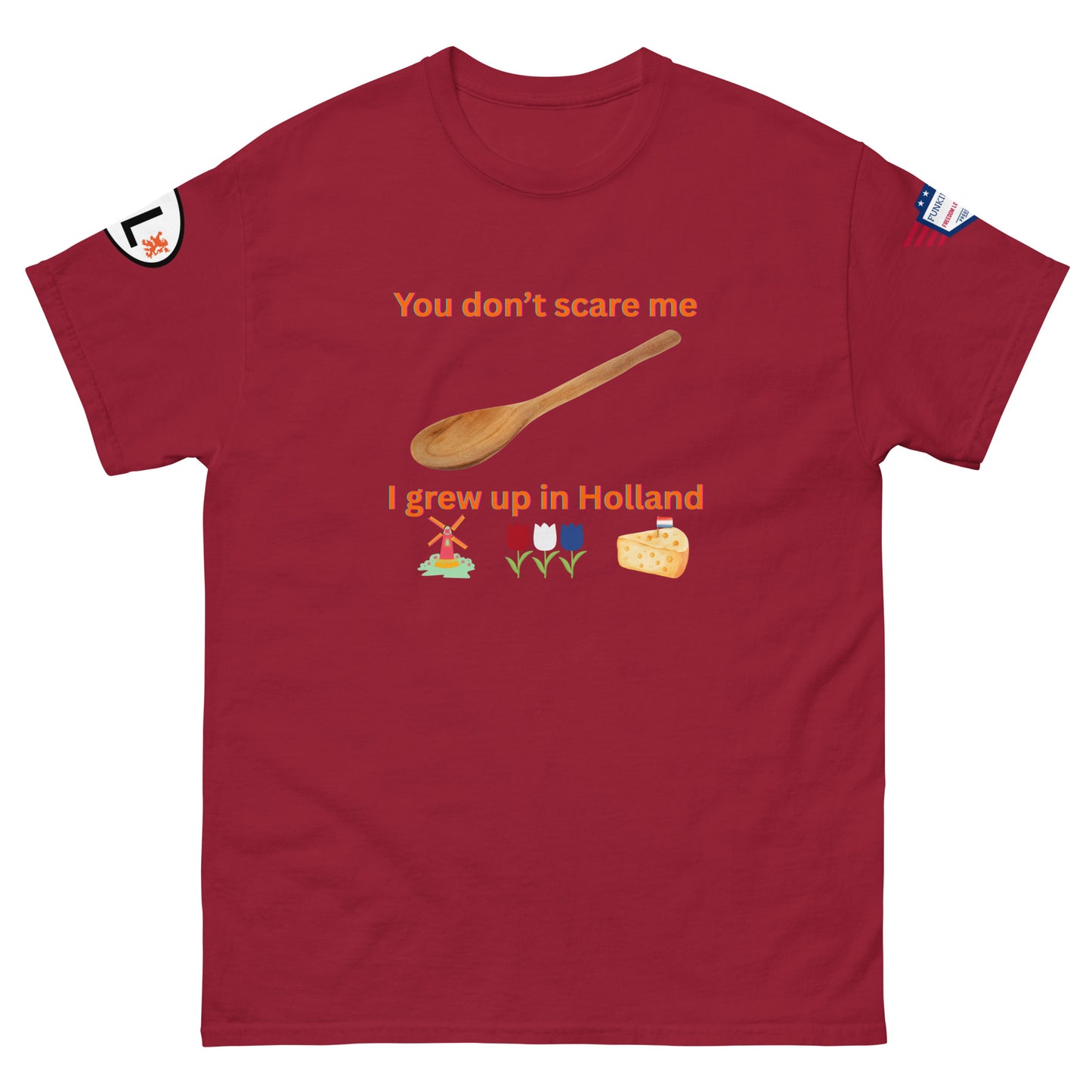 Front view of maroon unisex tee with orange "You don't scare me I grew up in Holland" text, defiant spoon, Dutch windmill, tulips, cheese, sleeve details