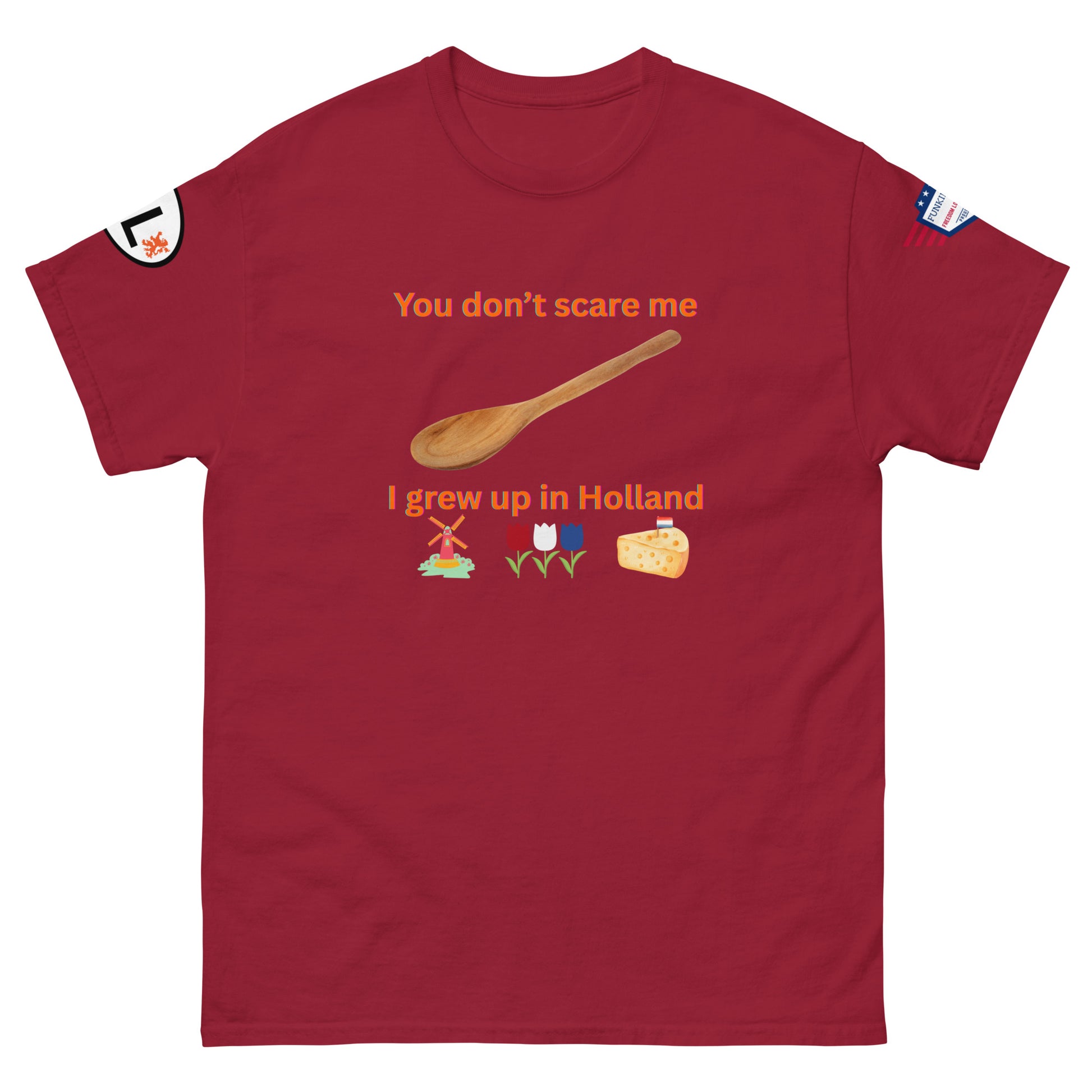 Front view of maroon unisex tee with orange "You don't scare me I grew up in Holland" text, defiant spoon, Dutch windmill, tulips, cheese, sleeve details