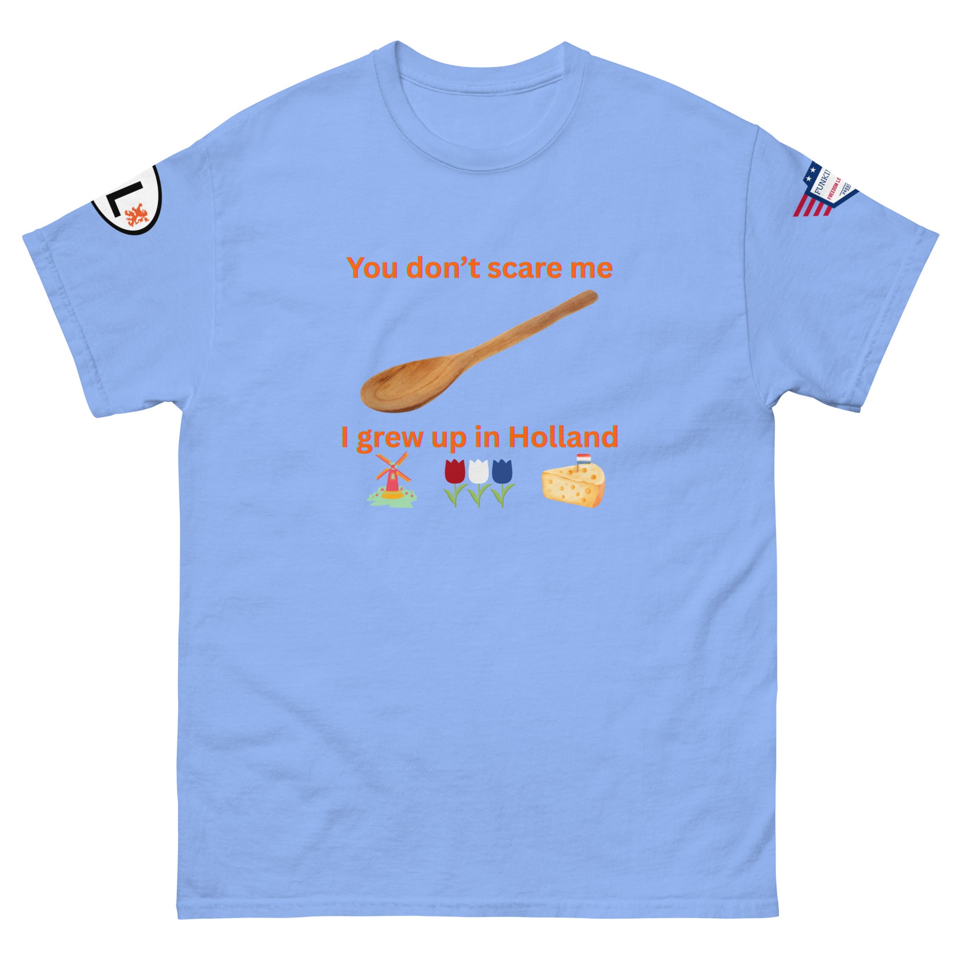 Front view of sky blue unisex tee with orange "You don't scare me, I grew up in Holland" print, wooden spoon, windmill/tulip/cheese emojis, sleeve patches