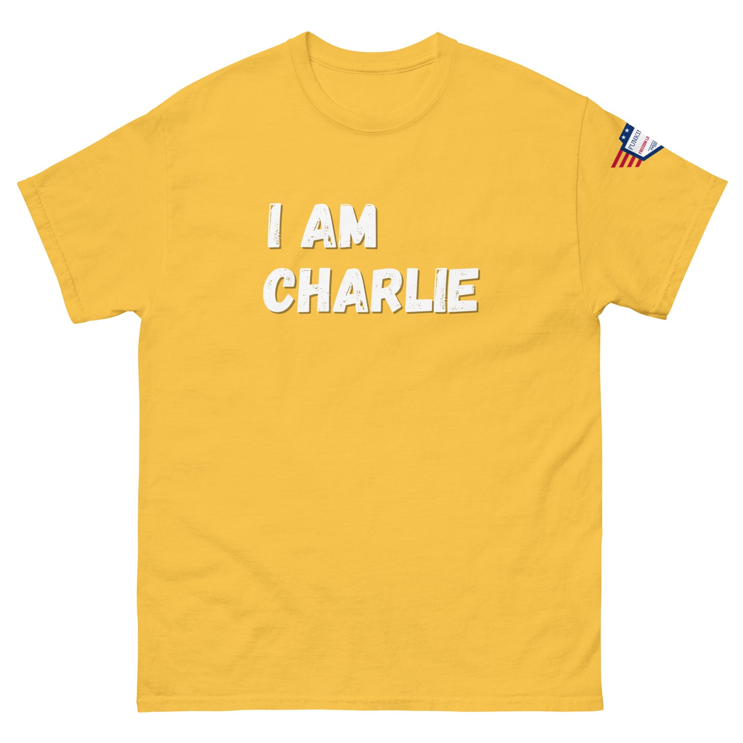 Front view of mustard yellow unisex tee with bold white "I AM CHARLIE" print and small American flag sleeve patch