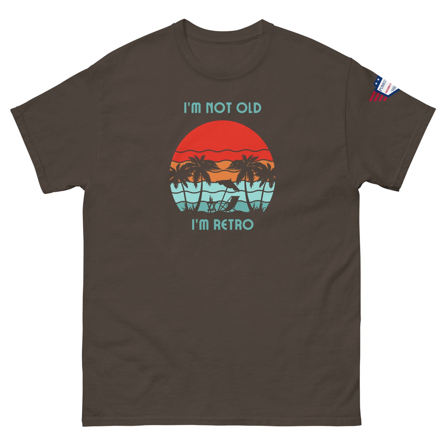 Front view of brown unisex t-shirt featuring "I'm not old I'm retro" over red sun, teal water palms graphic, US flag patch