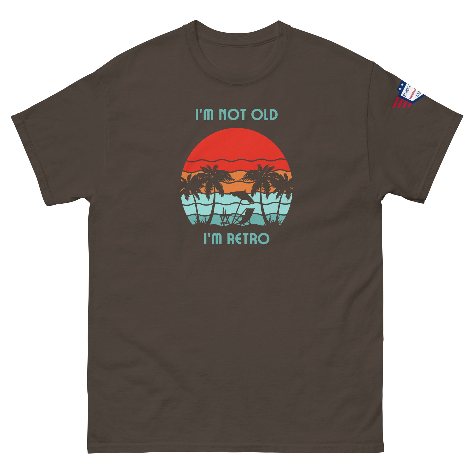 Front view of brown unisex t-shirt featuring "I'm not old I'm retro" over red sun, teal water palms graphic, US flag patch
