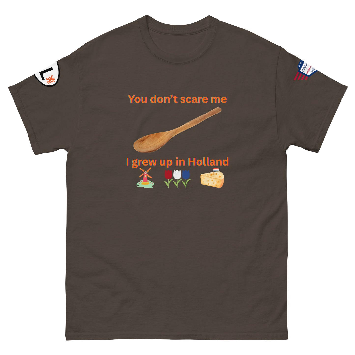 Front view of dark brown unisex tee with orange "You don't scare me, I grew up in Holland" print, wooden spoon, windmill/tulip/cheese emojis, sleeve patches