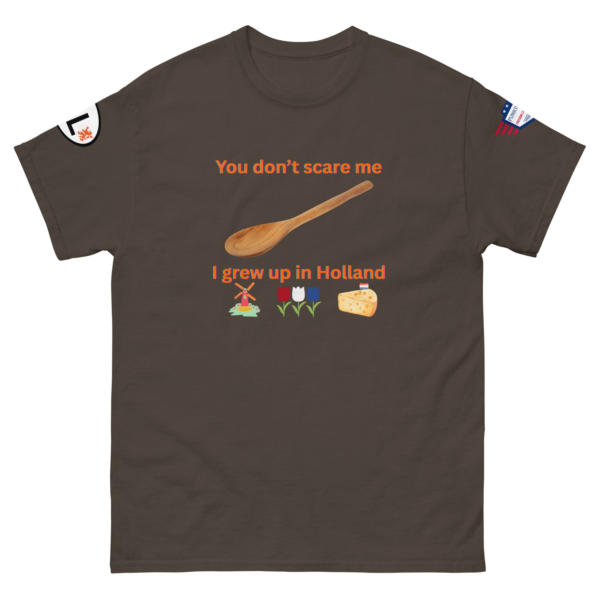 Front view of dark brown unisex tee with orange "You don't scare me, I grew up in Holland" print, wooden spoon, windmill/tulip/cheese emojis, sleeve patches