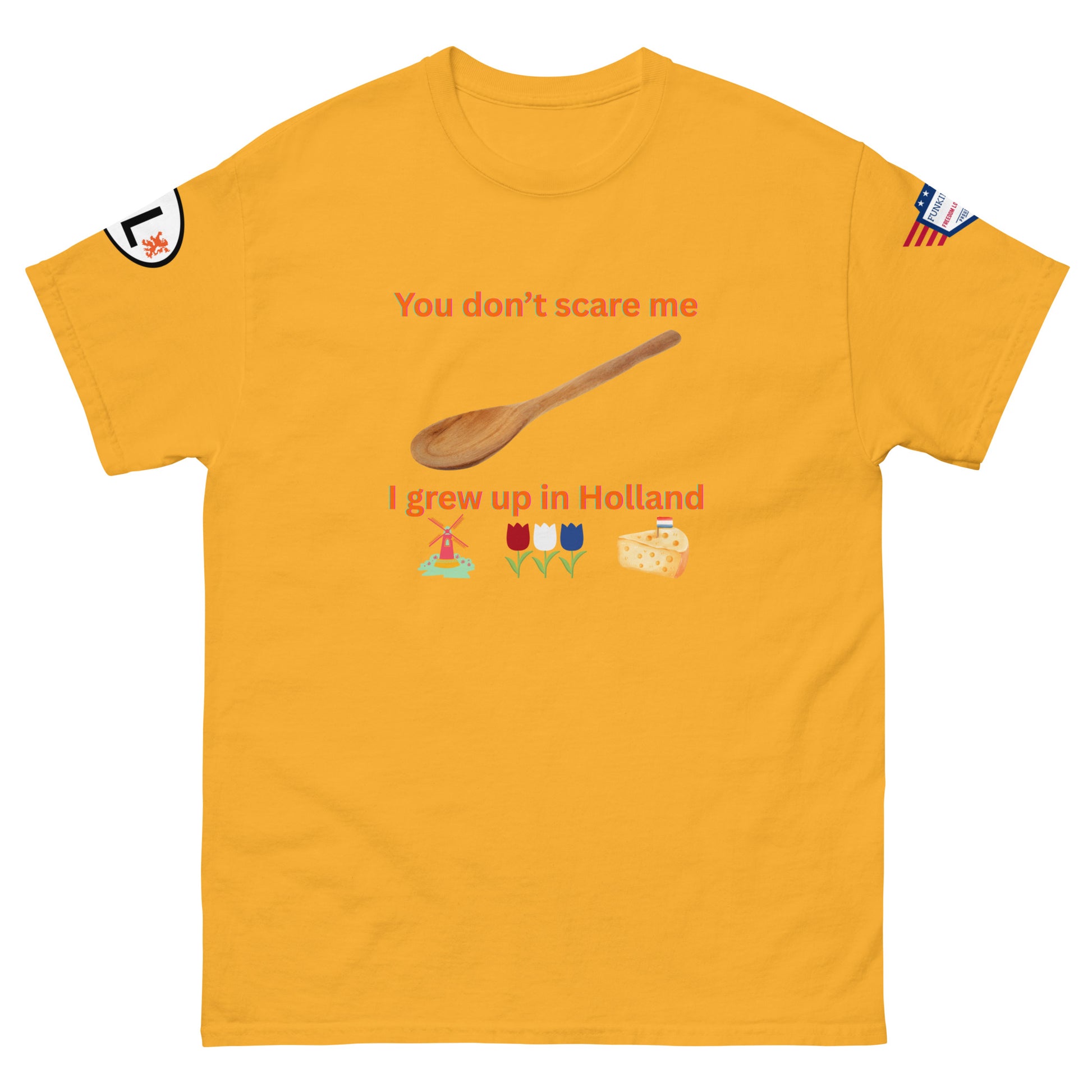 Front view of gold yellow unisex tee with orange "You don't scare me, I grew up in Holland" print, wooden spoon, windmill/tulip/cheese emojis, sleeve patches