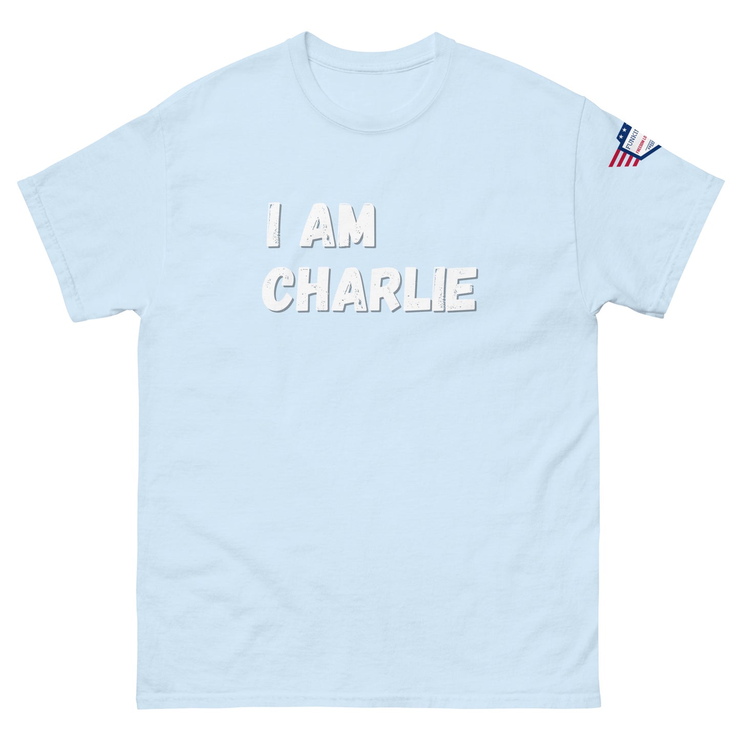 Light blue unisex tee front view, bold white "I AM CHARLIE" graphic, small US flag sleeve patch