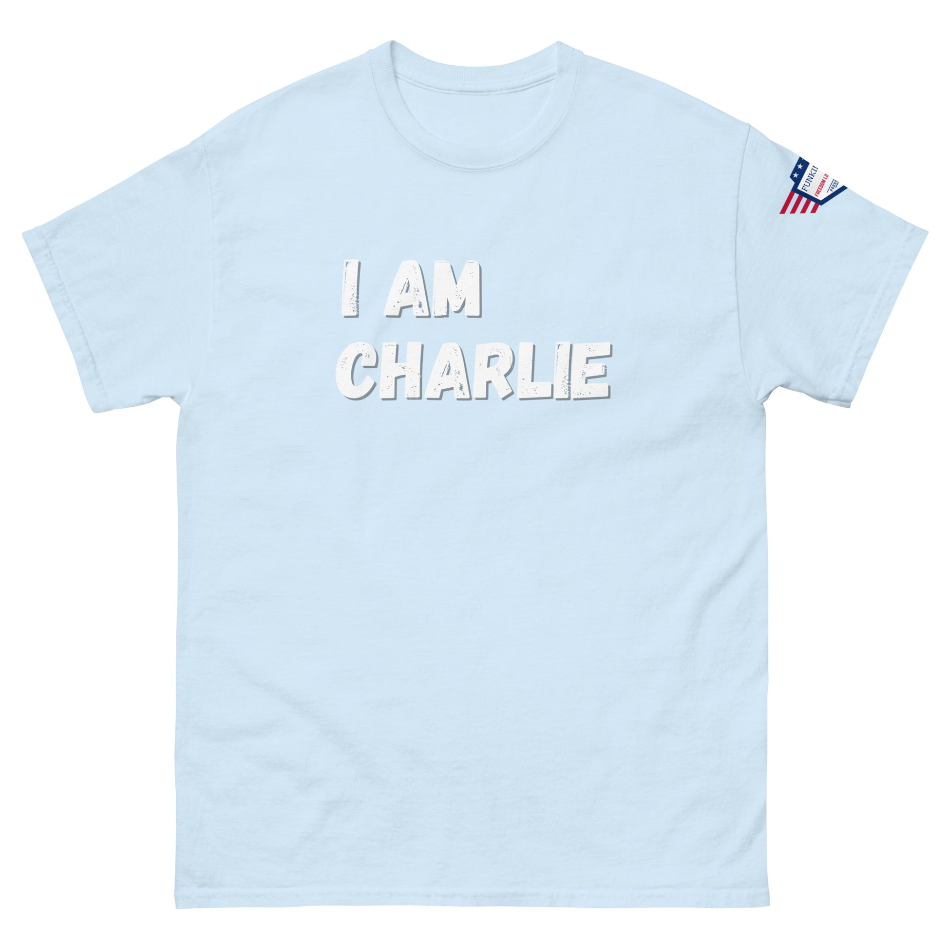 Light blue unisex tee front view, bold white "I AM CHARLIE" graphic, small US flag sleeve patch