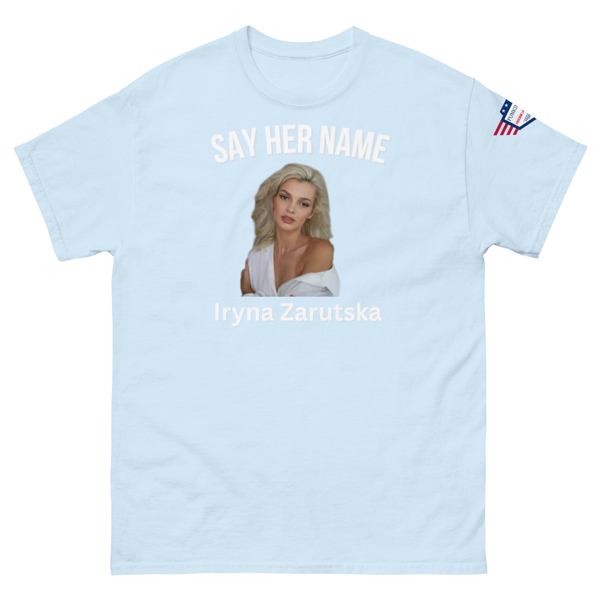 Front view of baby blue unisex tee with "SAY HER NAME" arch, Iryna Zarzutska blonde portrait, name text below, US flag sleeve patch