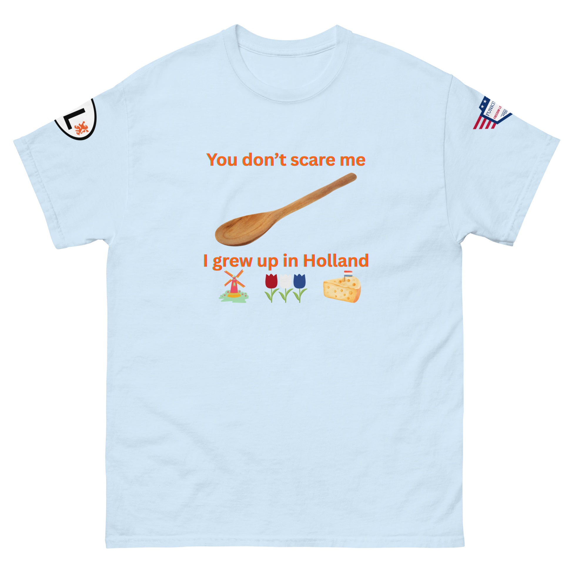 Front view of light blue unisex tee with "You don't scare me, I grew up in Holland" orange print, wooden spoon, windmill, tulips, cheese emojis