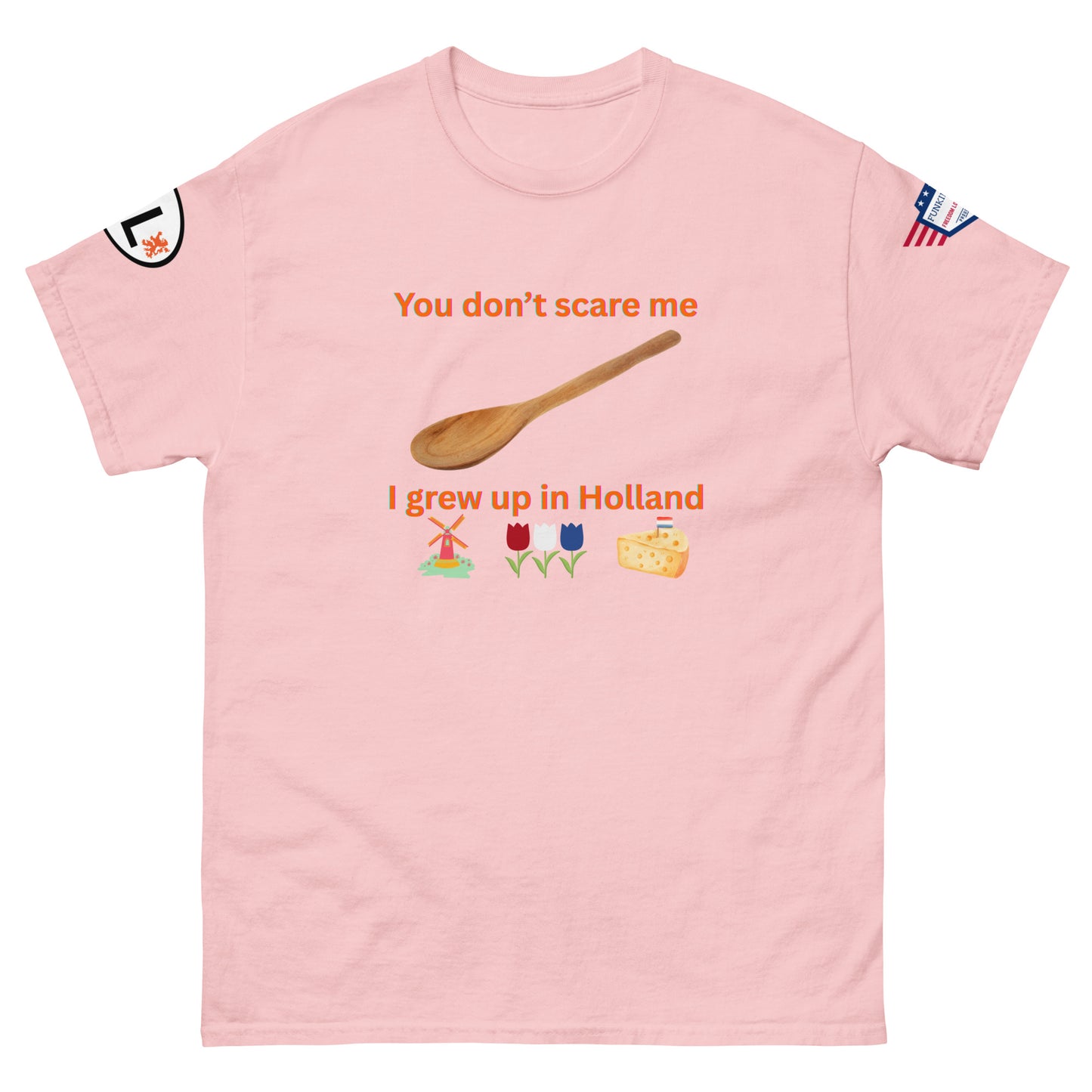 Front view of light pink unisex tee featuring "You don't scare me, I grew up in Holland" orange text, spoon, Dutch windmill, tulips, cheese graphics