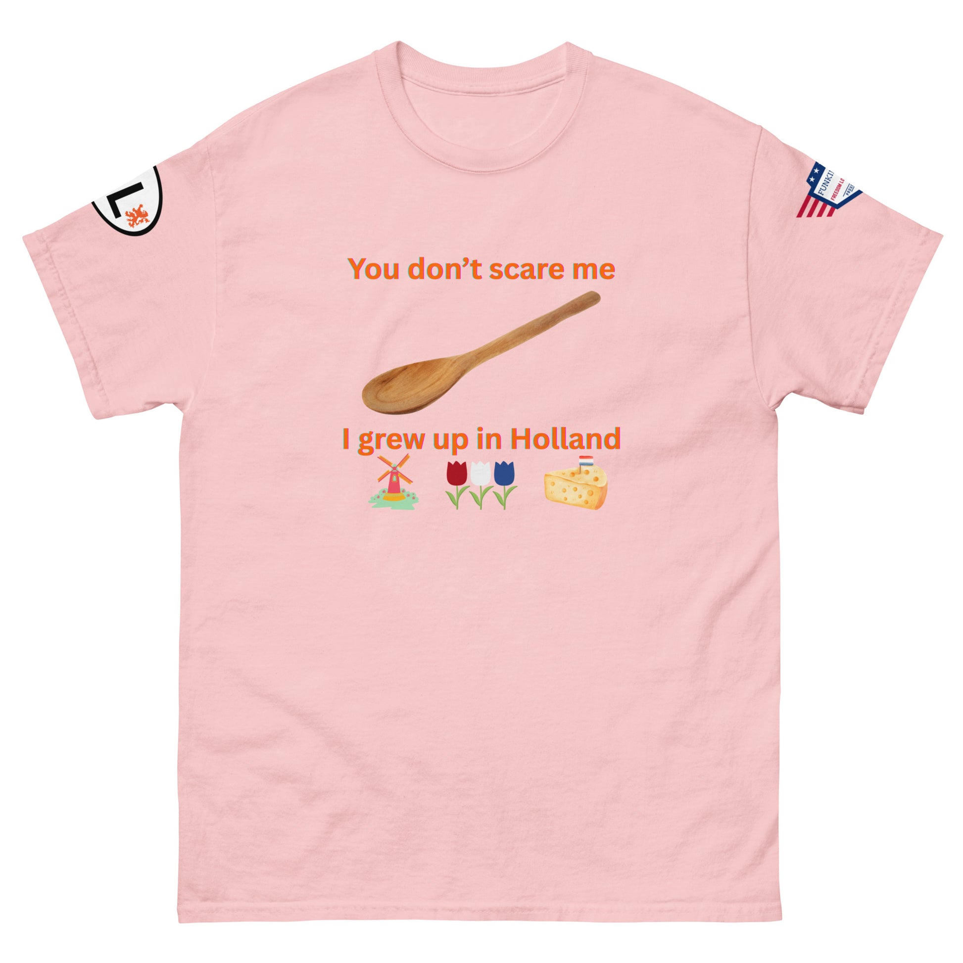 Front view of light pink unisex tee featuring "You don't scare me, I grew up in Holland" orange text, spoon, Dutch windmill, tulips, cheese graphics