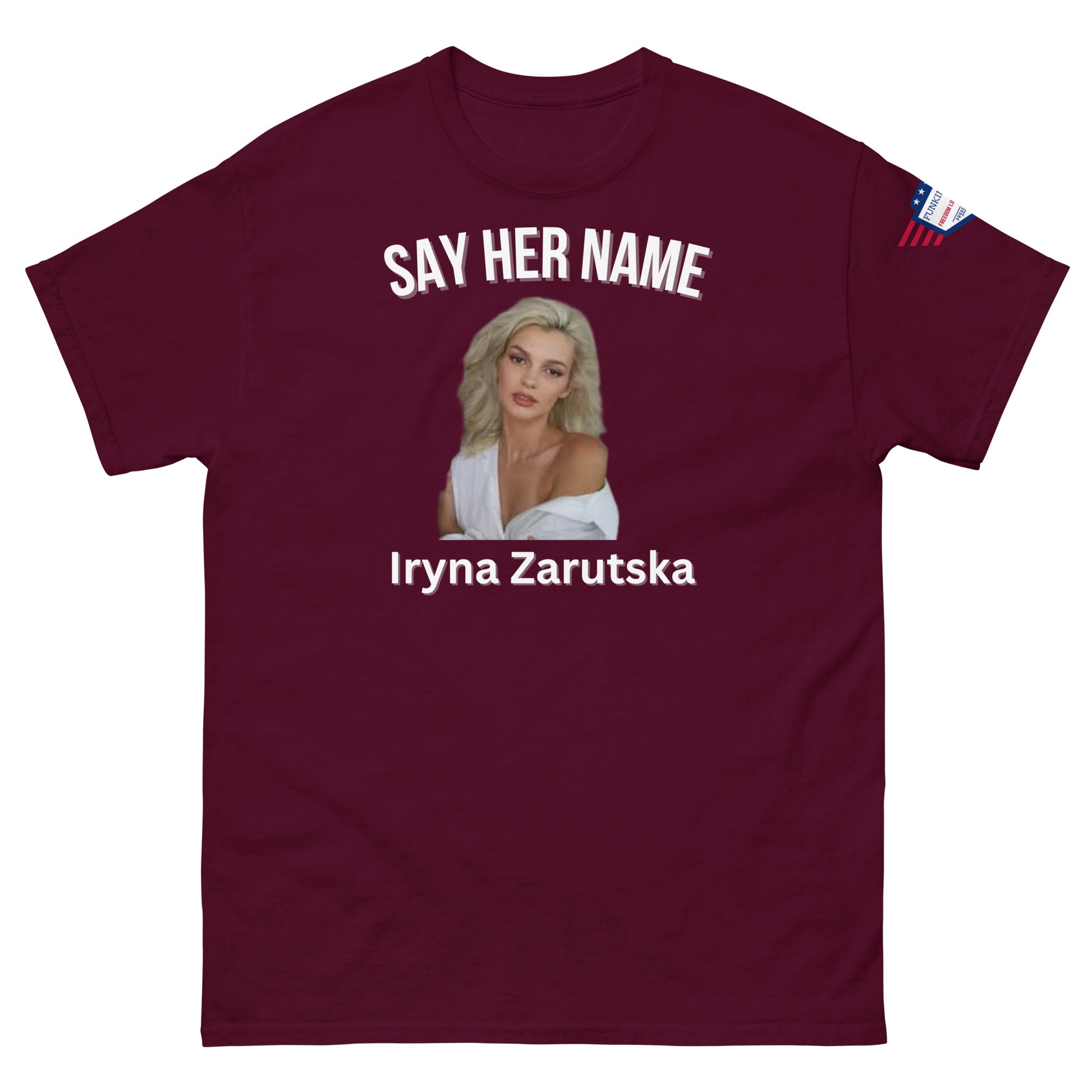 Front view of maroon unisex meme tee: "SAY HER NAME" over blonde Iryna Zarzutska portrait, name below, American flag patch