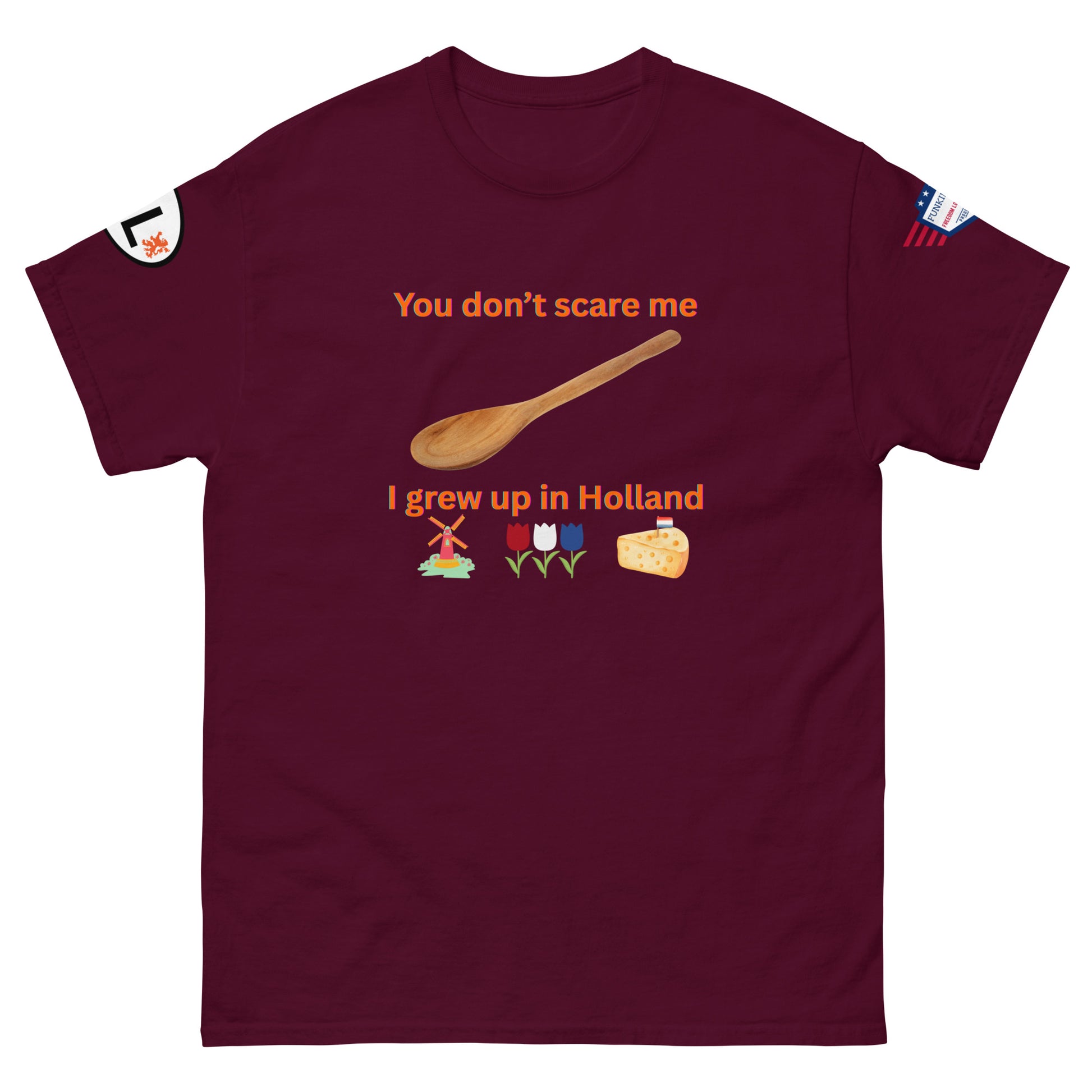 Front view of maroon unisex tee showing "You don't scare me, I grew up in Holland" print with orange spoon, windmill, tulips, cheese
