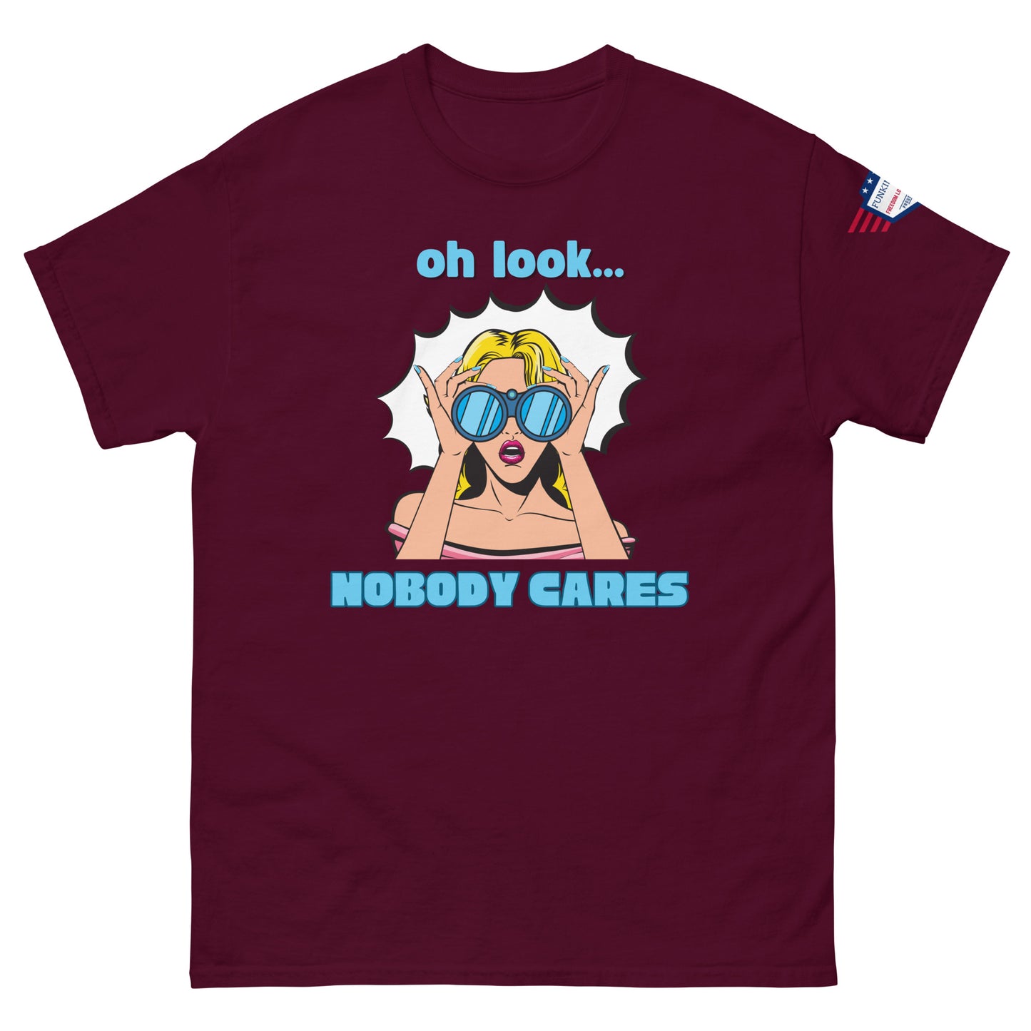 Front view of maroon unisex t-shirt showing "oh look... NOBODY CARES" comic-style blonde bombshell, flag on sleeve
