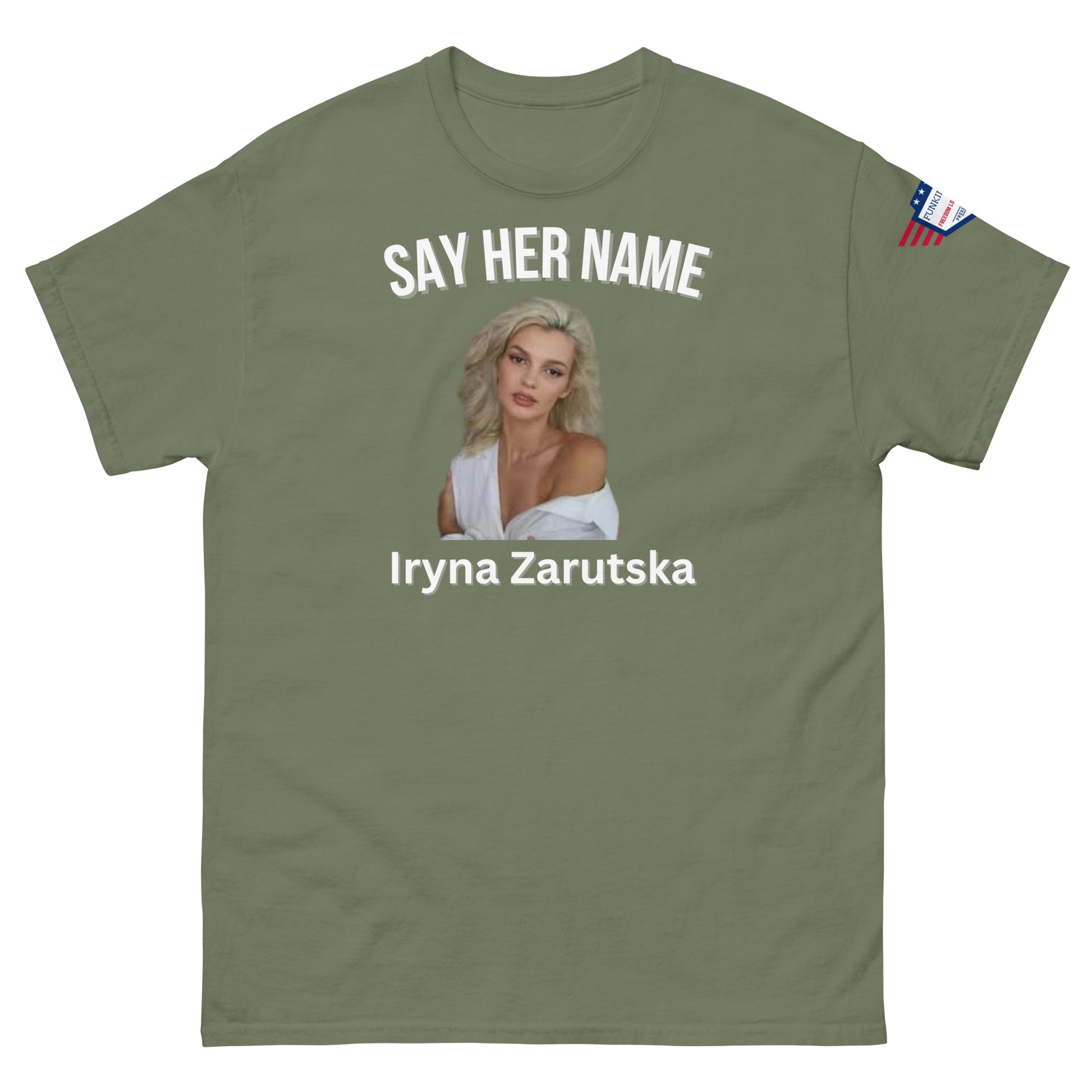 Front view of olive green tee showing "SAY HER NAME", Iryna Zarzutska's wavy blonde portrait, text details, flag sleeve label