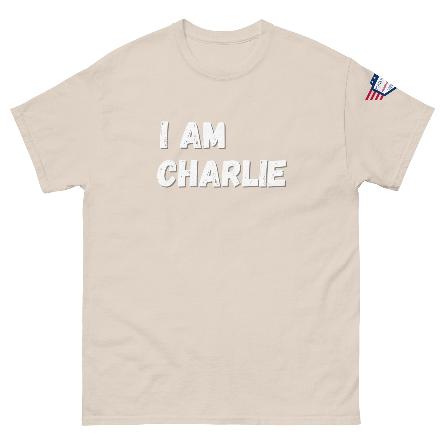 Tan unisex tee front with white "I AM CHARLIE" print, small US flag on sleeve