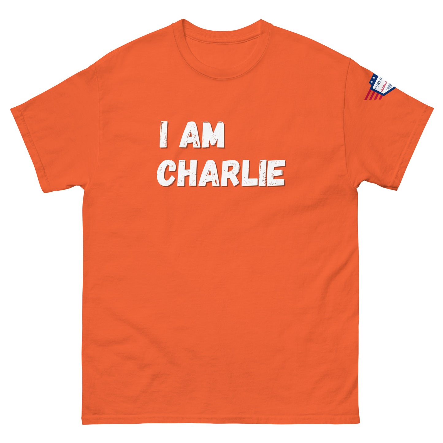Orange unisex tee front, white "I AM CHARLIE" bold text, US flag right sleeve