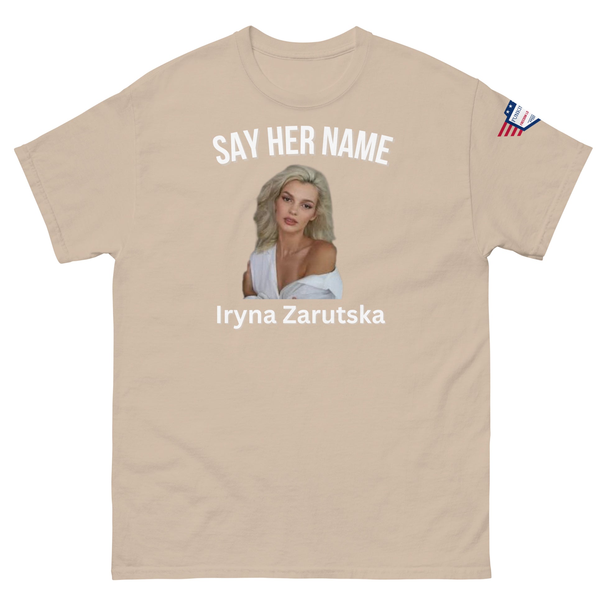 Front view of light ash unisex tee: "SAY HER NAME" over Iryna Zarzutska portrait, name in white, subtle flag sleeve patch