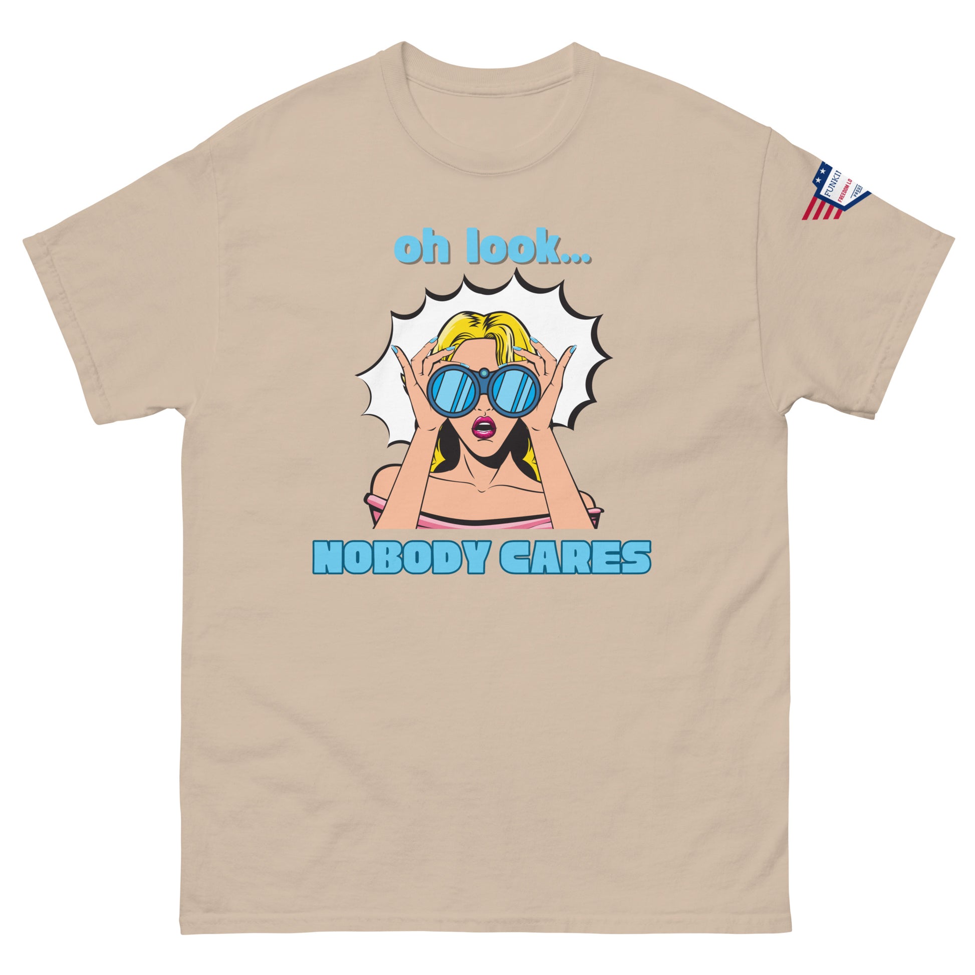 Front view of sand beige unisex t-shirt showing "oh look... NOBODY CARES" pop-art print, USA sleeve patch