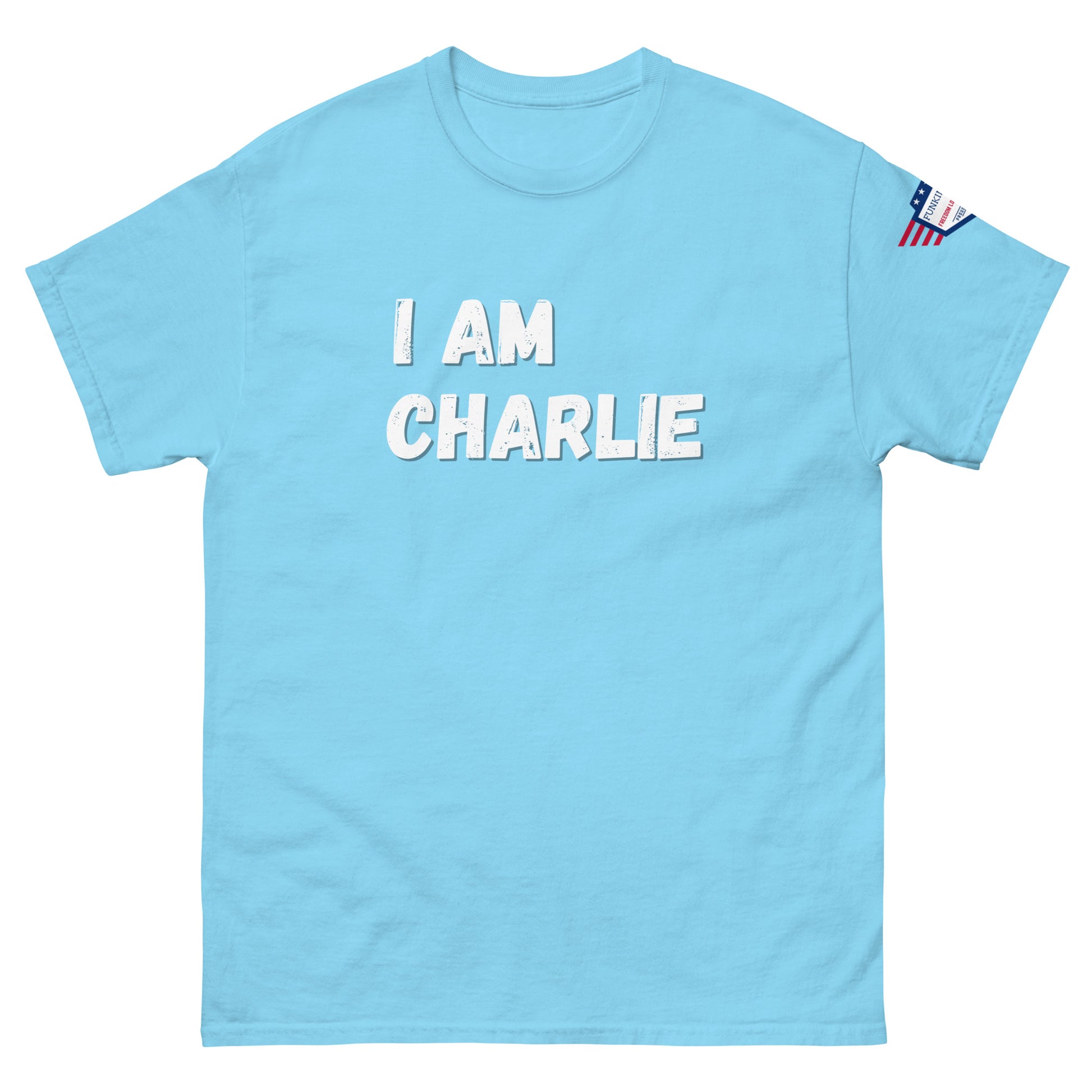 Front view of sky blue unisex tee with bold white "I AM CHARLIE" graphic and small USA flag sleeve patch