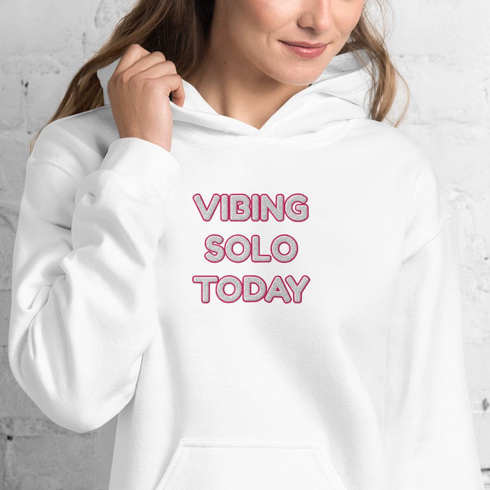 Front view of smiling model in white "Vibing Solo Today" embroidered hoodie, pink thread details