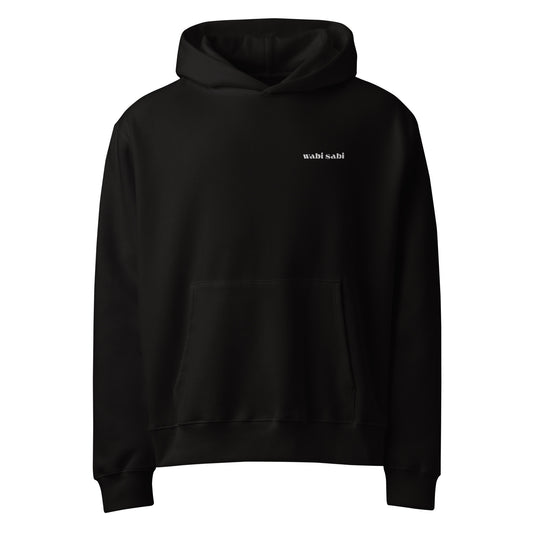Front view of black oversized heavyweight hoodie with subtle white "wabi sabi" script on left chest