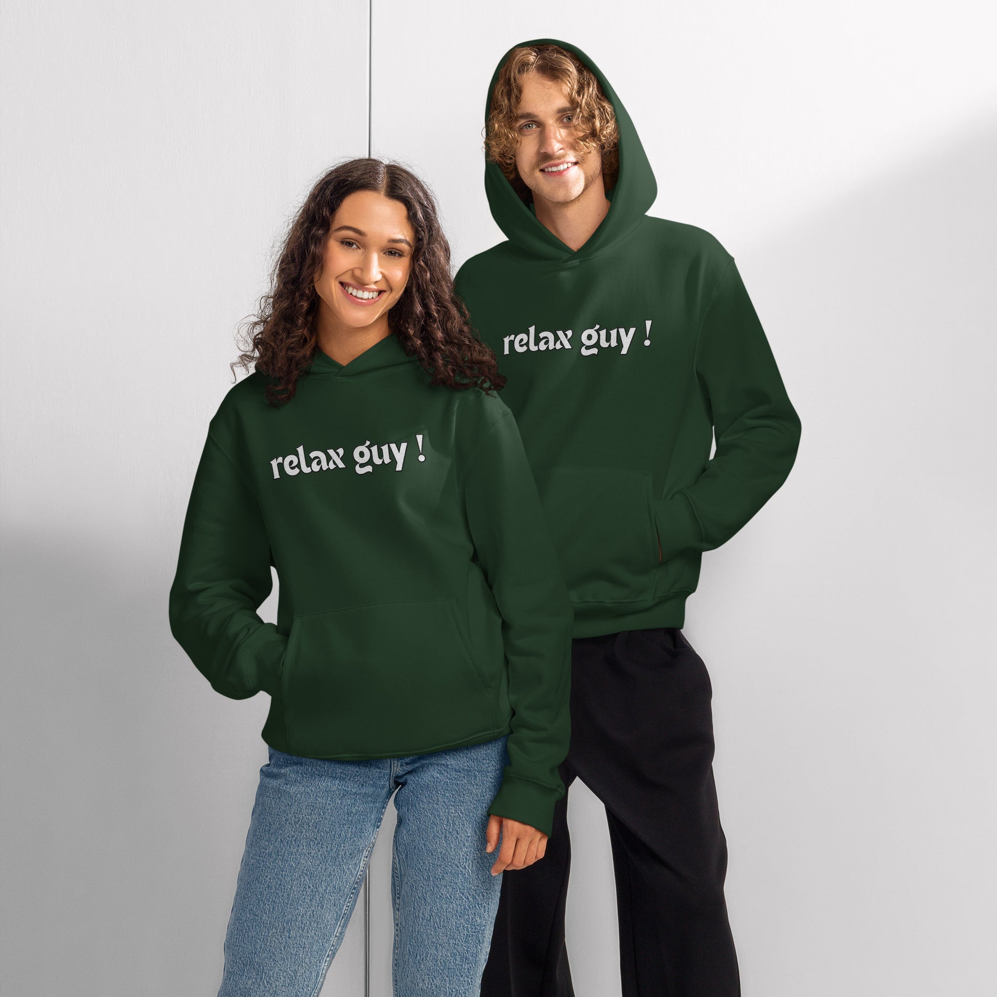 Couple posing in matching forest green oversized hoodies, front view with "relax guy!" print